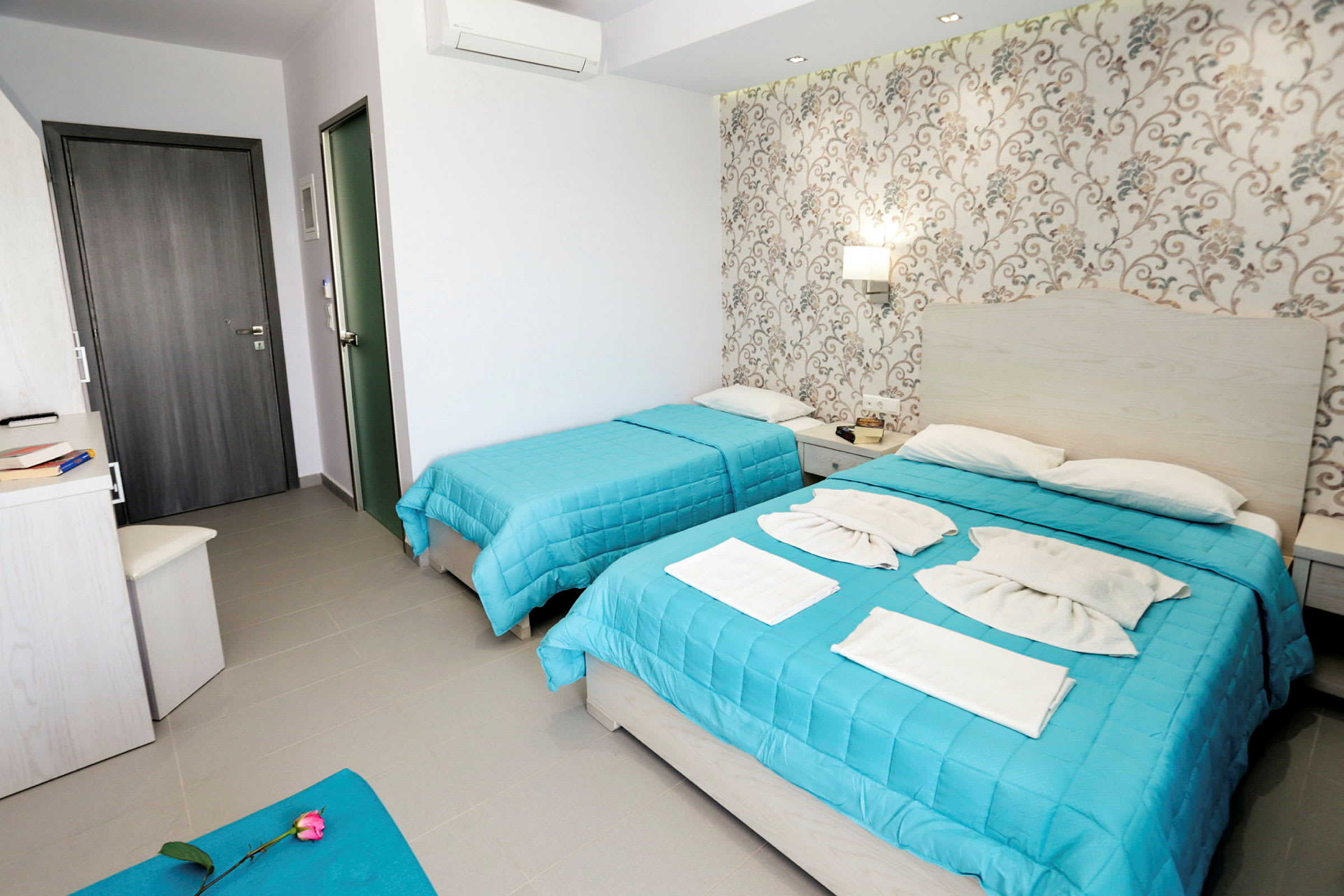 Ett hotellrum med två sängar med blå överkast, sido bord och dekorerad vägg. (AI-genererad text)
