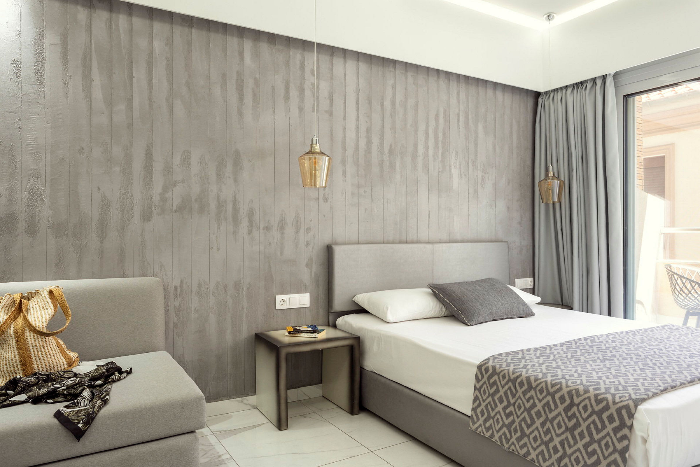 Hotellrum med grå inredning, säng och sidobord. (AI-genererad text)