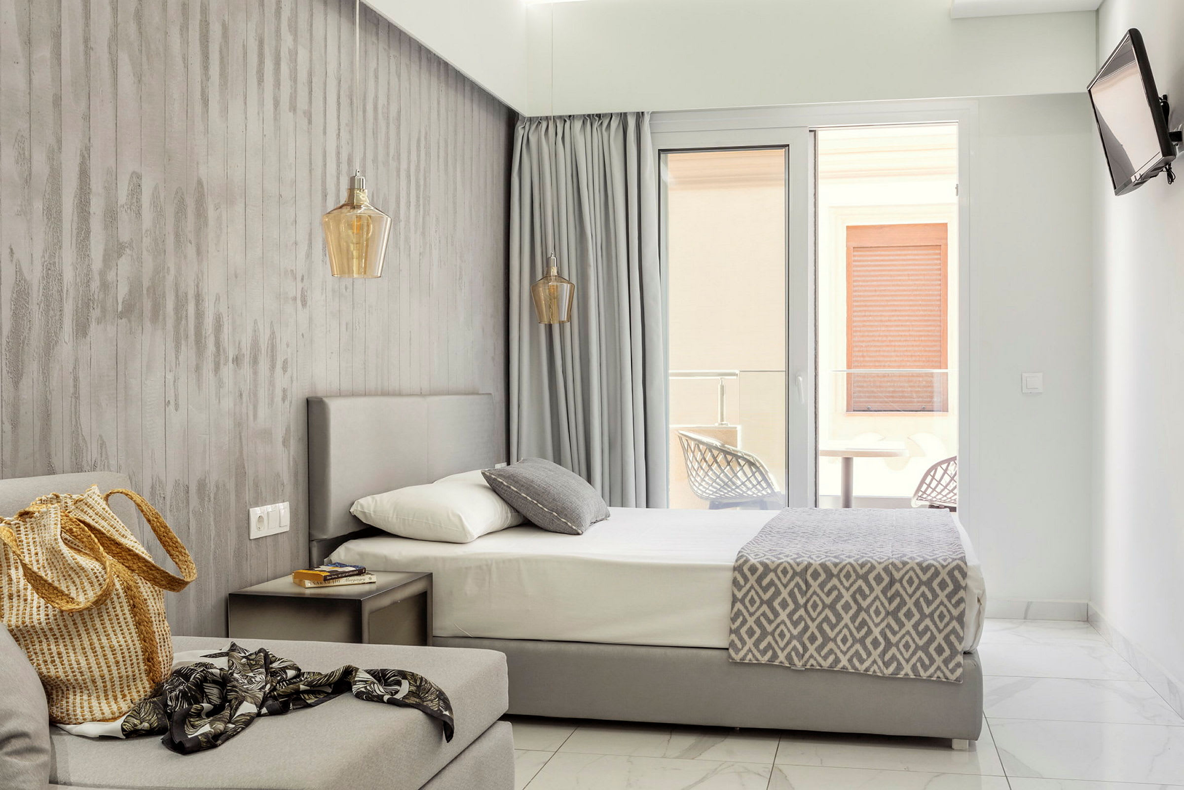 Modernt hotellrum med säng, soffa och balkongdörr. (AI-genererad text)