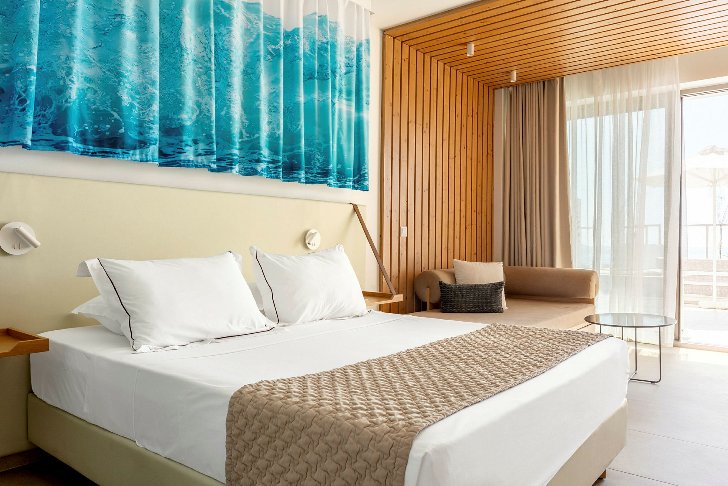 Ett hotellrum med en stor säng, vita lakan och en beige överkast. Väggen är av träpanel och ett stort fönster med gardiner ger utsikt utomhus. (AI-genererad text)