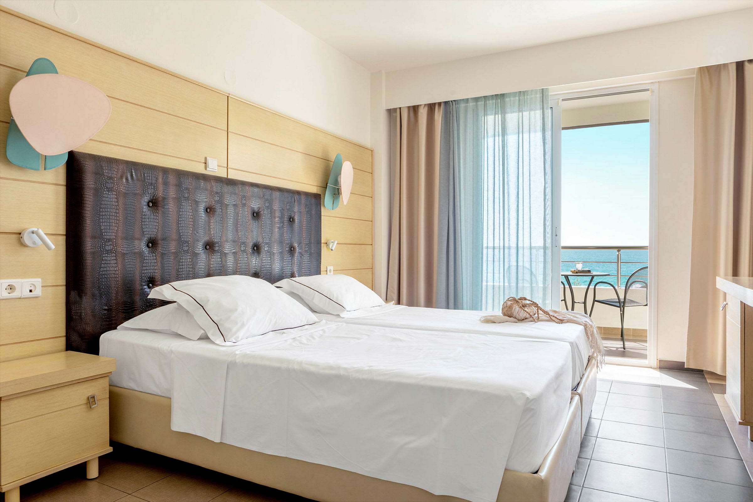Ett hotellrum med en dubbelsäng och en balkong med utsikt över havet. (AI-genererad text)
