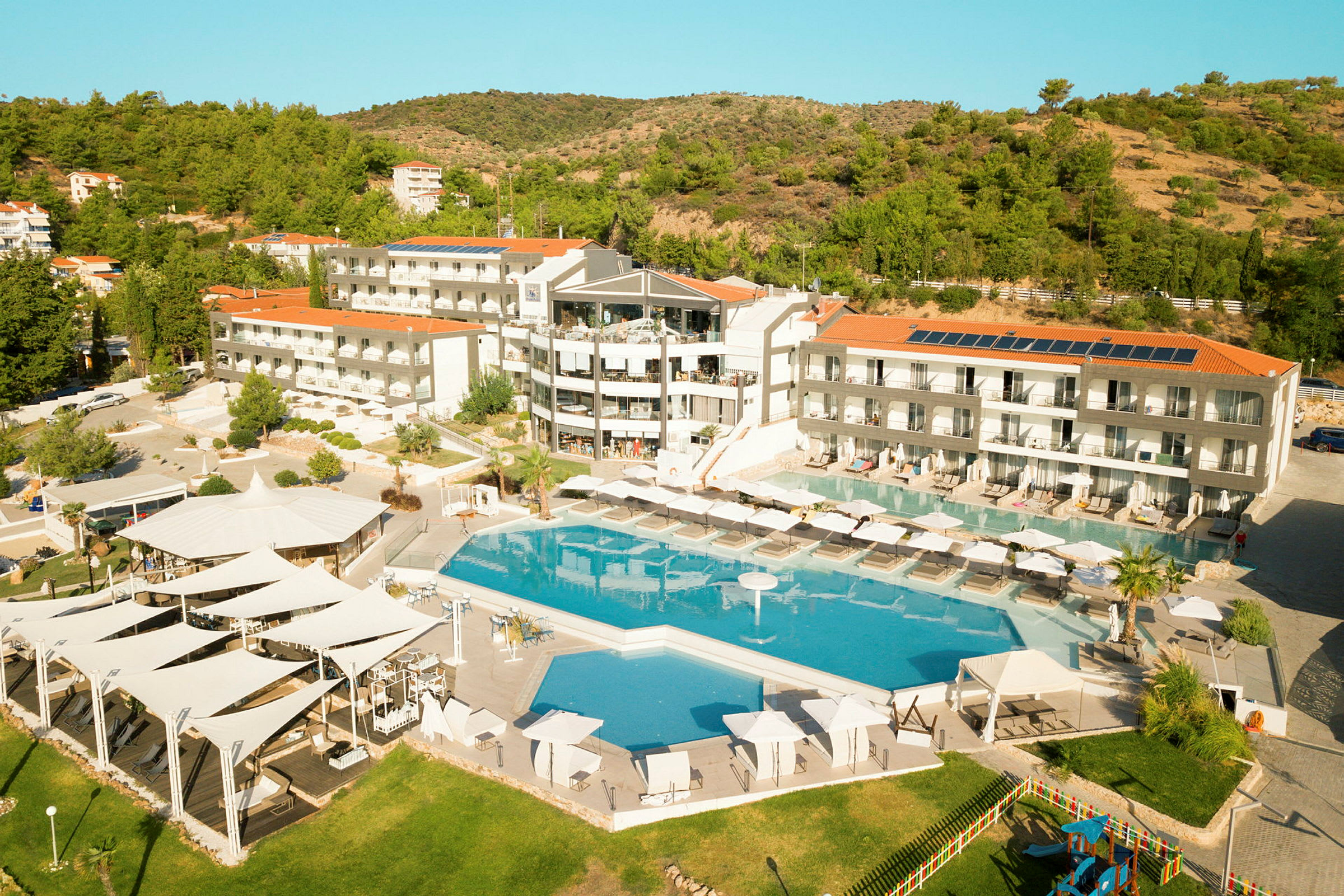 En hotellanläggning med pool, solstolar och omgivande grönska. (AI-genererad text)