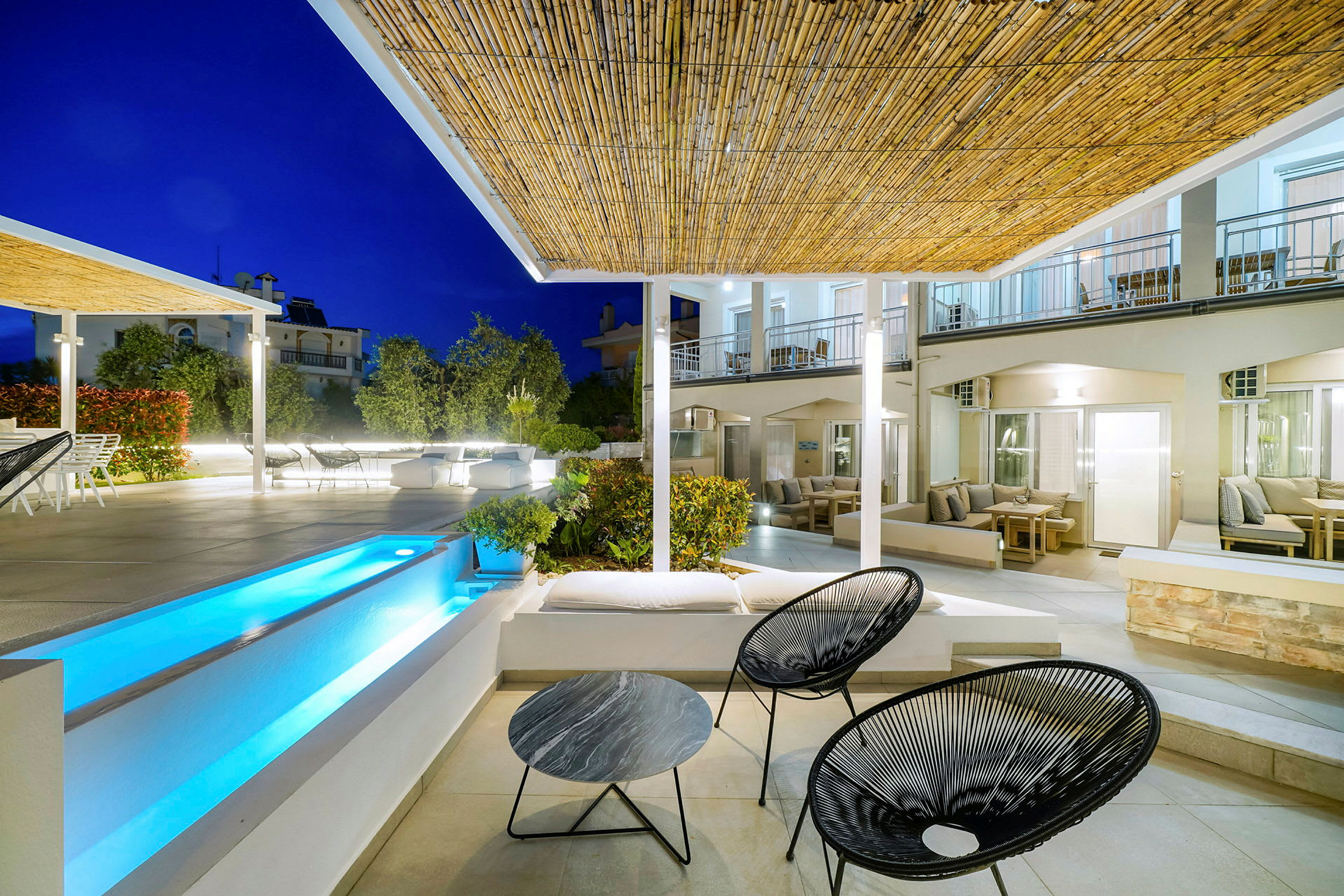 Utemiljö kvällsbelysning med sittmöbler, pool och byggnad. (AI-genererad text)