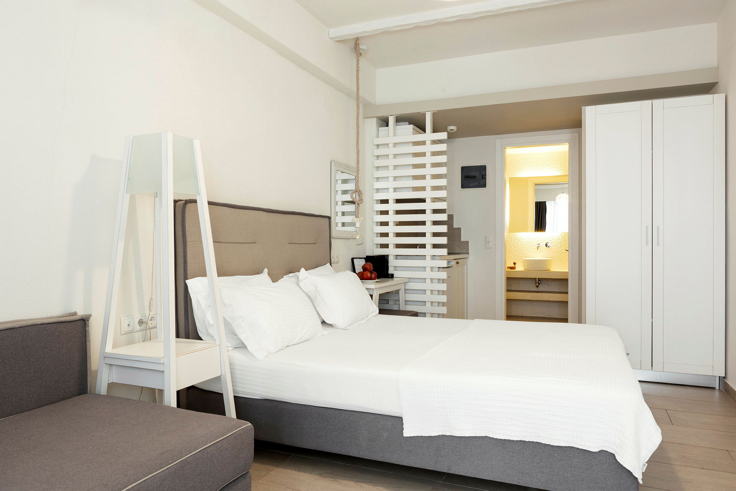 Ett modernt hotellrum med en dubbelsäng, en garderob och en synlig del av badrummet. (AI-genererad text)