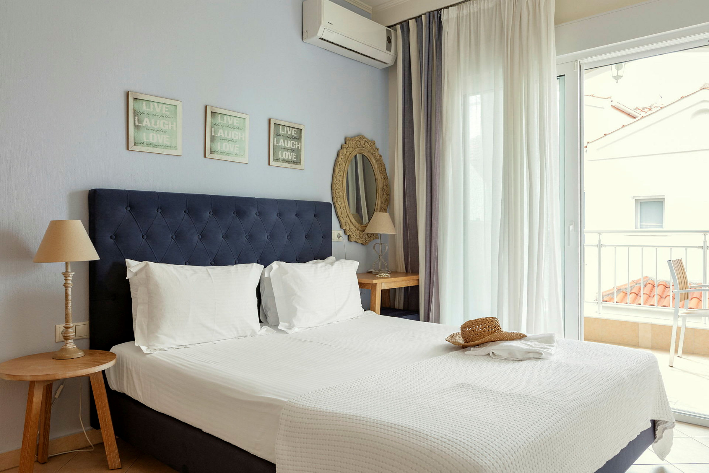 Ett hotellrum med en dubbelsäng, nattduksbord och utsikt över en terrass. (AI-genererad text)