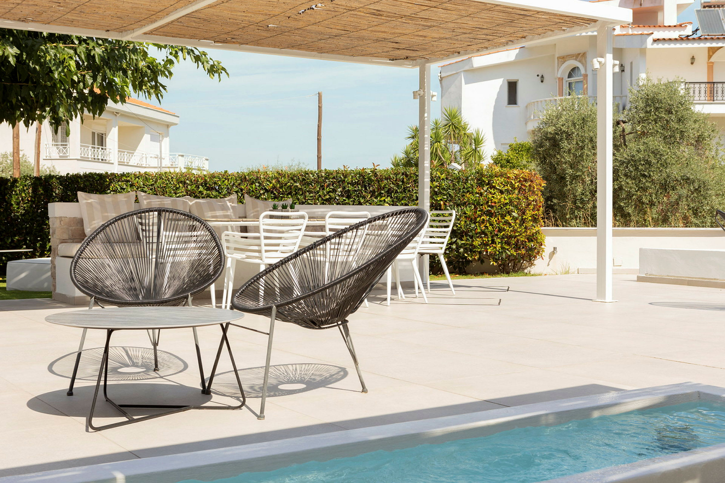 En uteservering med moderna stolar och bord vid en pool. (AI-genererad text)
