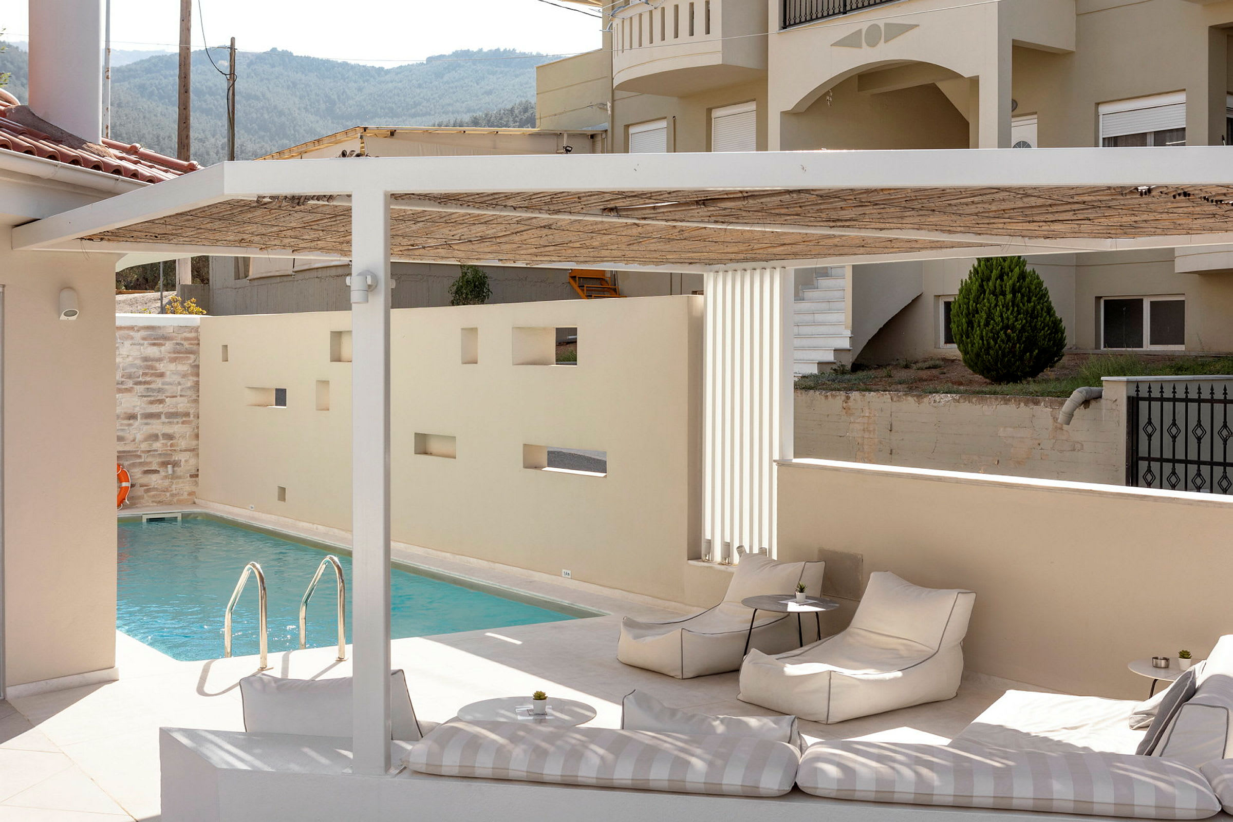 Utomhusområde med pool och sittplatser. Beige byggnad i bakgrunden. (AI-genererad text)