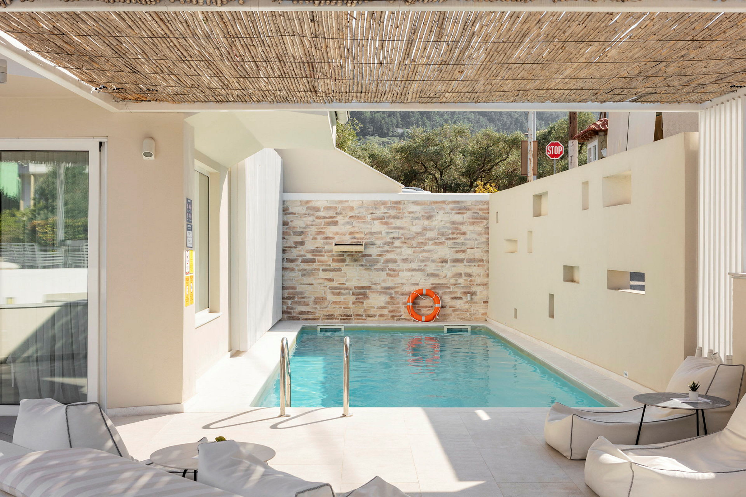 En mindre swimmingpool med solskyddande tak och en mur med livboj. (AI-genererad text)