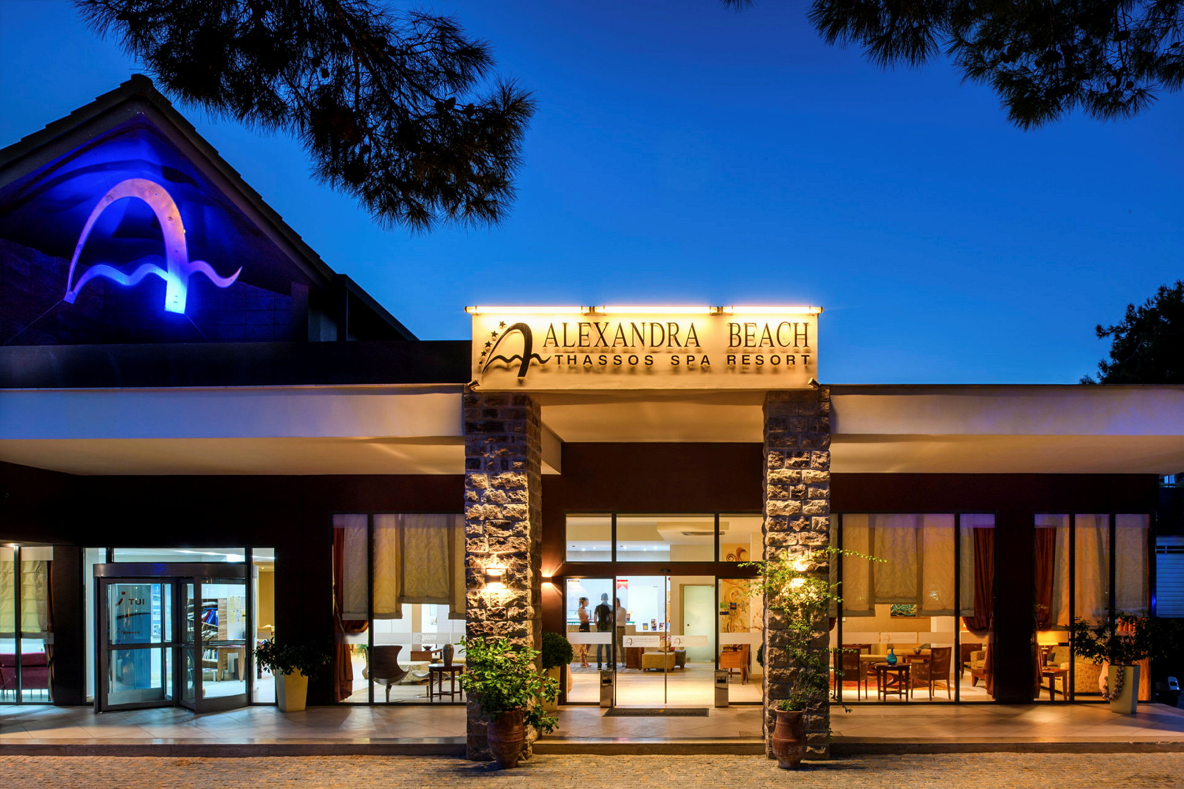 Framsidan av Alexandra Beach Thassos Spa Resort under kvällstid. (AI-genererad text)