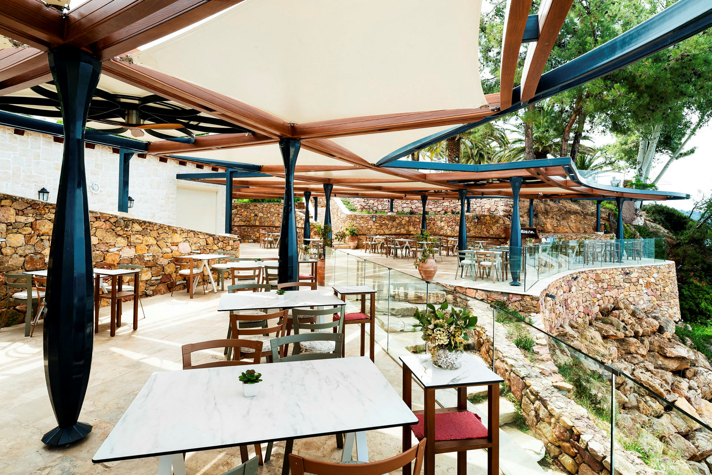 Restaurang på terrass täckt med tak och omgiven av stenmur. (AI-genererad text)