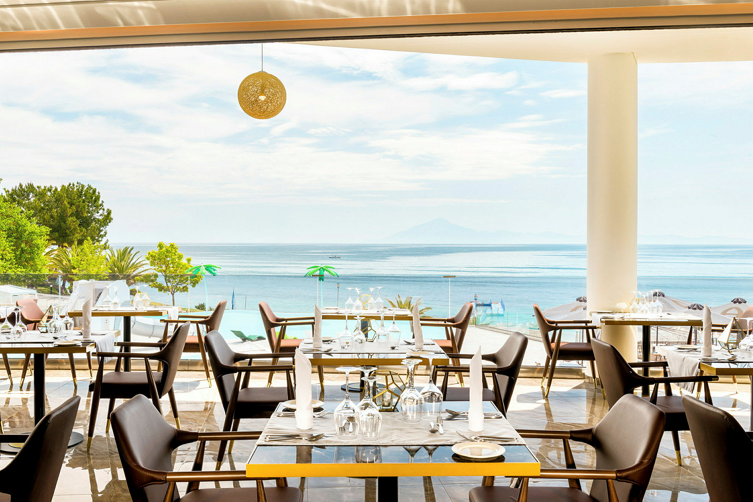 Restaurang med utsikt över havet, möblerade med bord och stolar. (AI-genererad text)