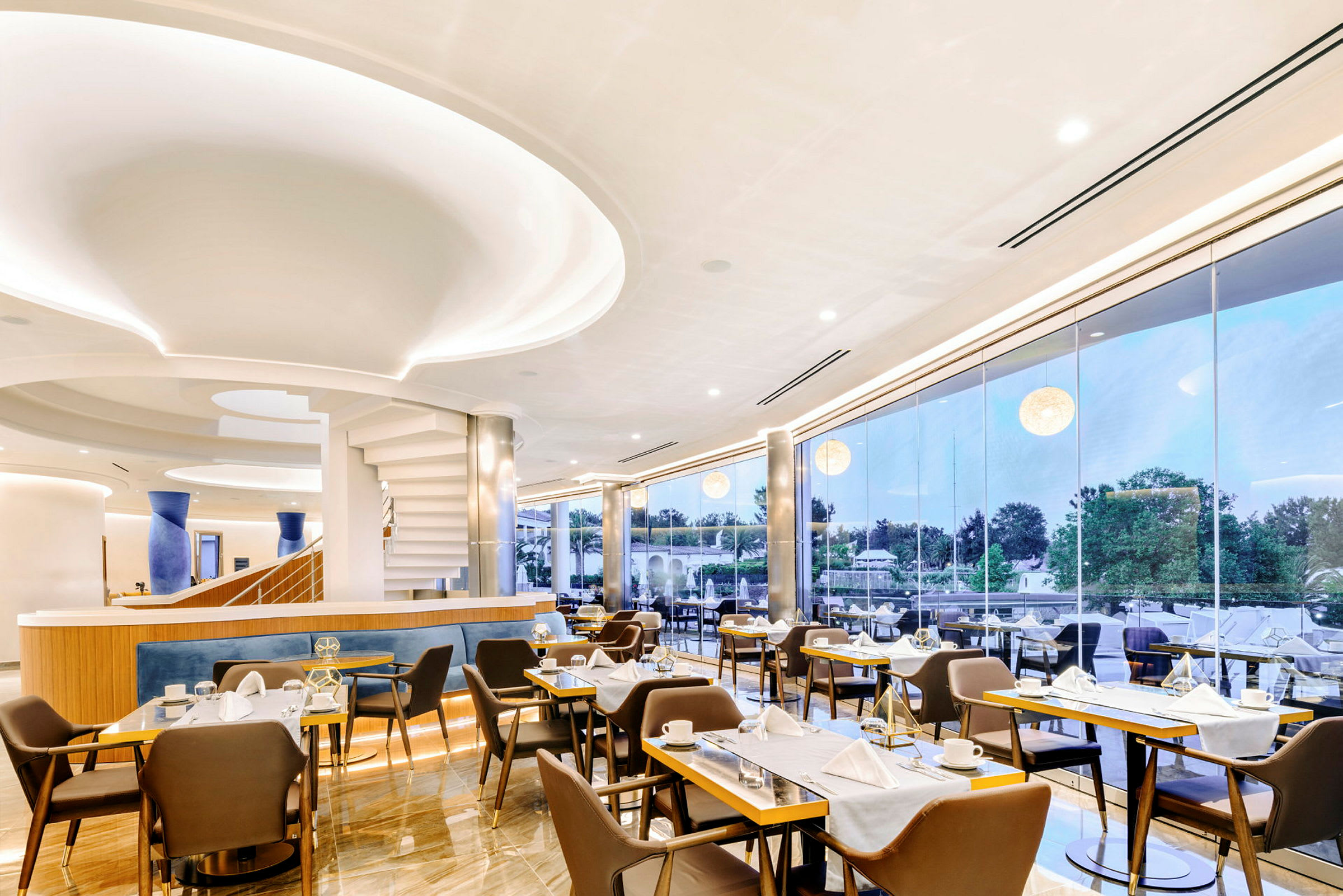 Modernt inredd restaurang med stora glasfönster ut mot grönska. (AI-genererad text)