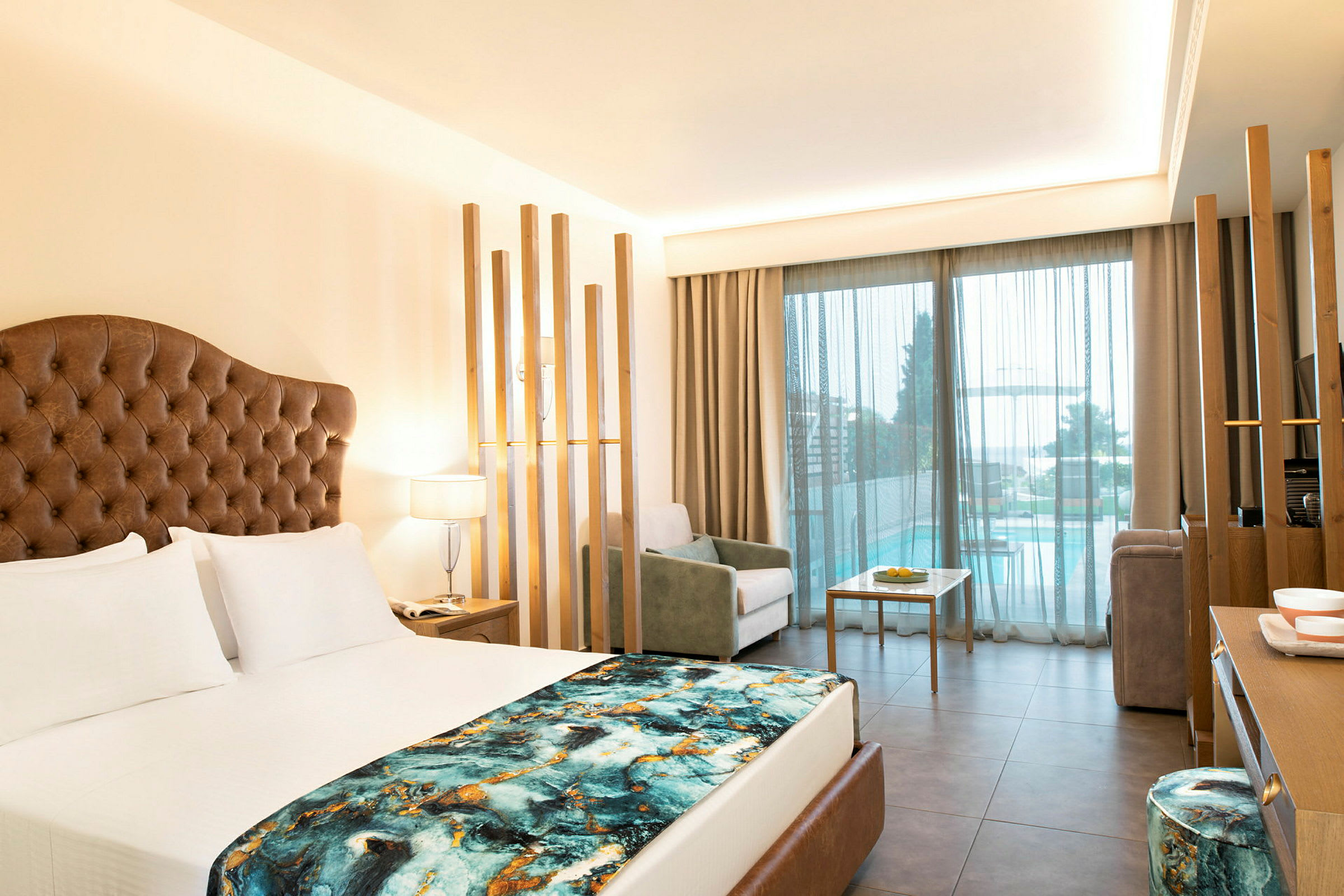 Bild av ett modernt hotellrum med en stor säng, sittgrupp och utsikt mot en terrass med pool. (AI-genererad text)