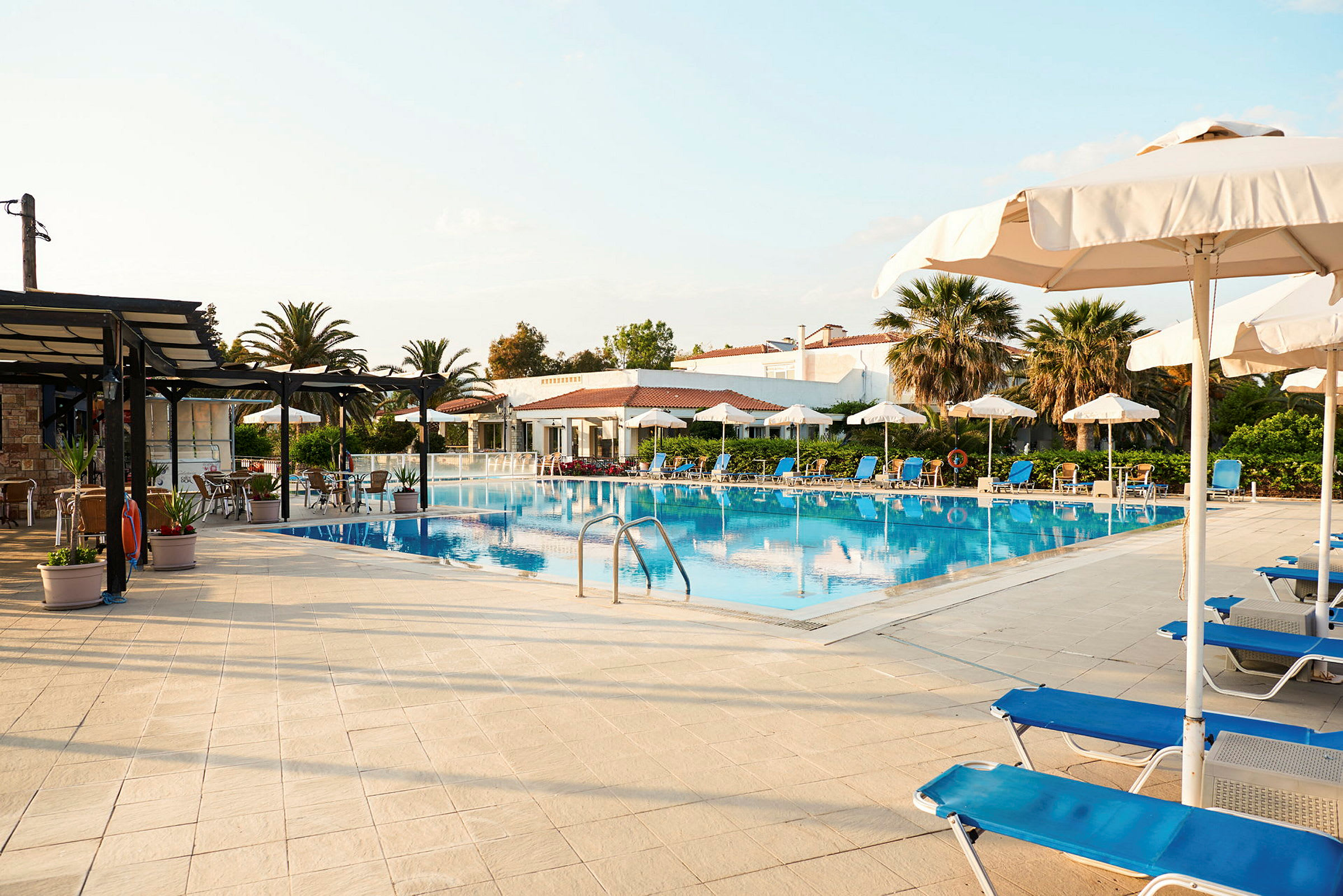 Bild av en pool med solstolar och parasoller omkring. (AI-genererad text)