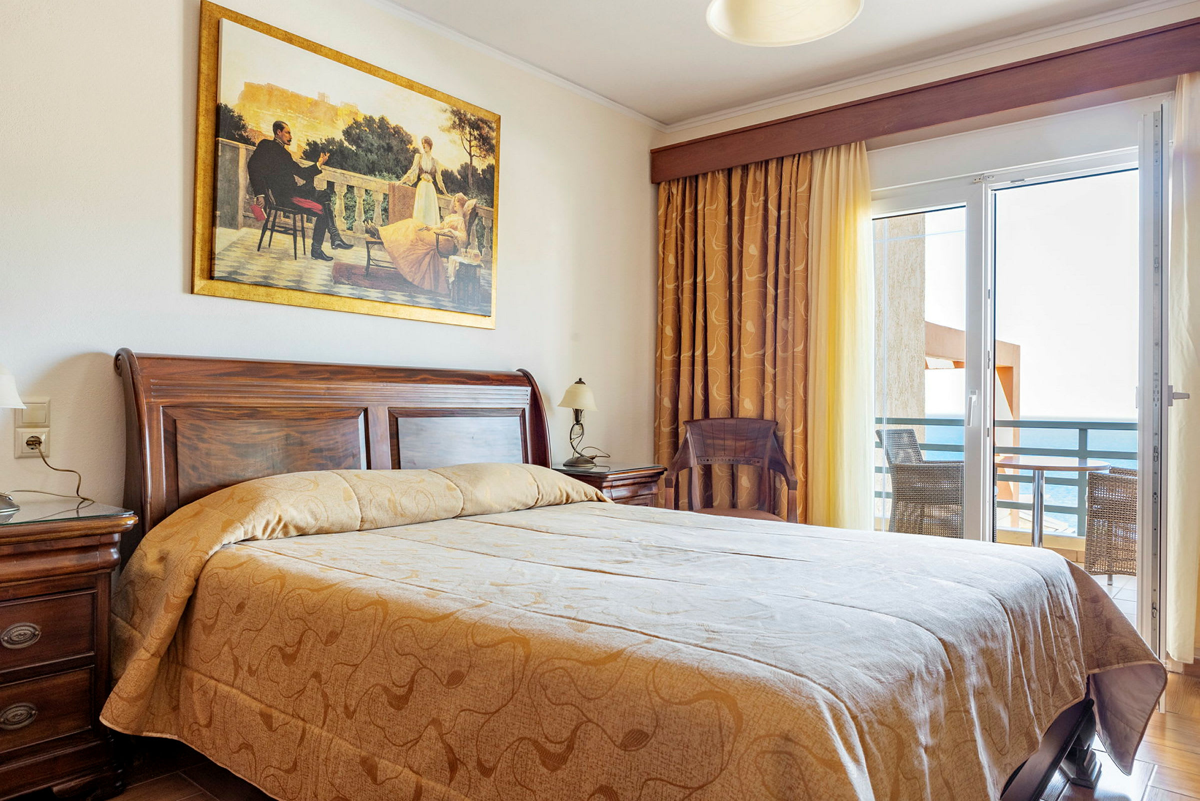 Ett hotellrum med en stor säng, trädetaljer och en balkong med havsutsikt. (AI-genererad text)