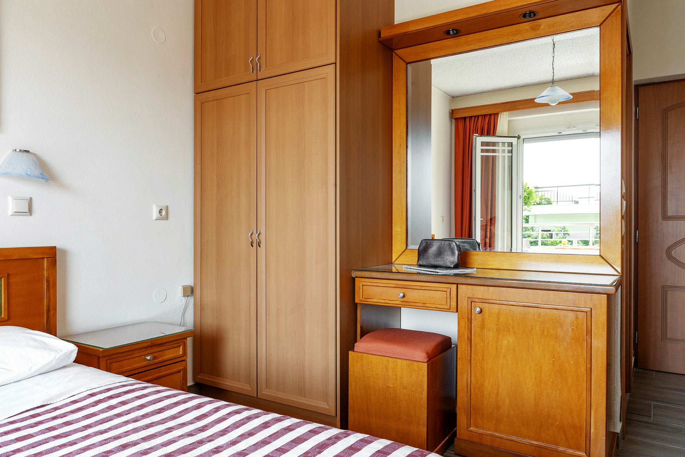 Hotelrum med garderob, skrivbord och spegel. (AI-genererad text)