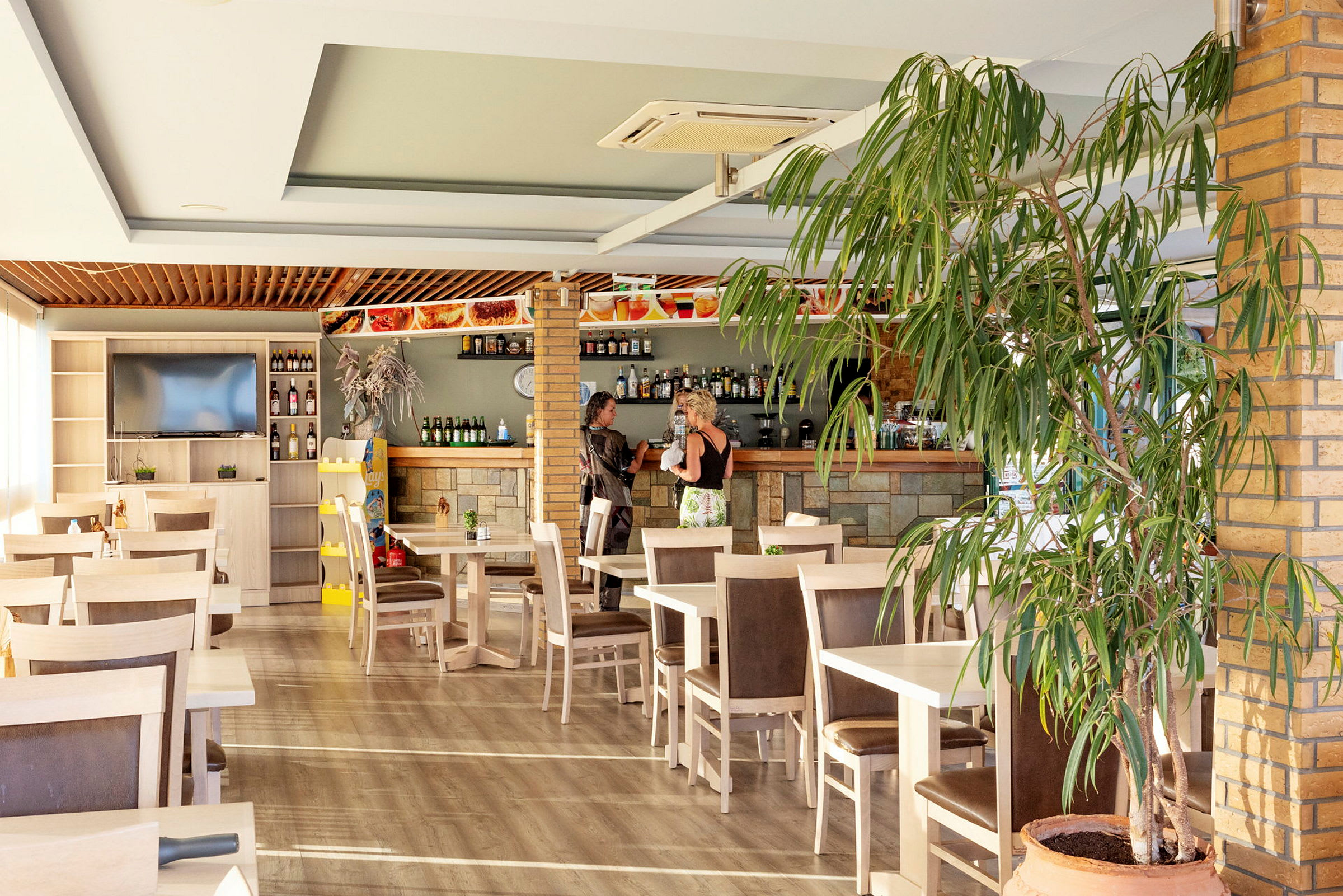 Restaurang med bord, stolar och en bardisk. (AI-genererad text)
