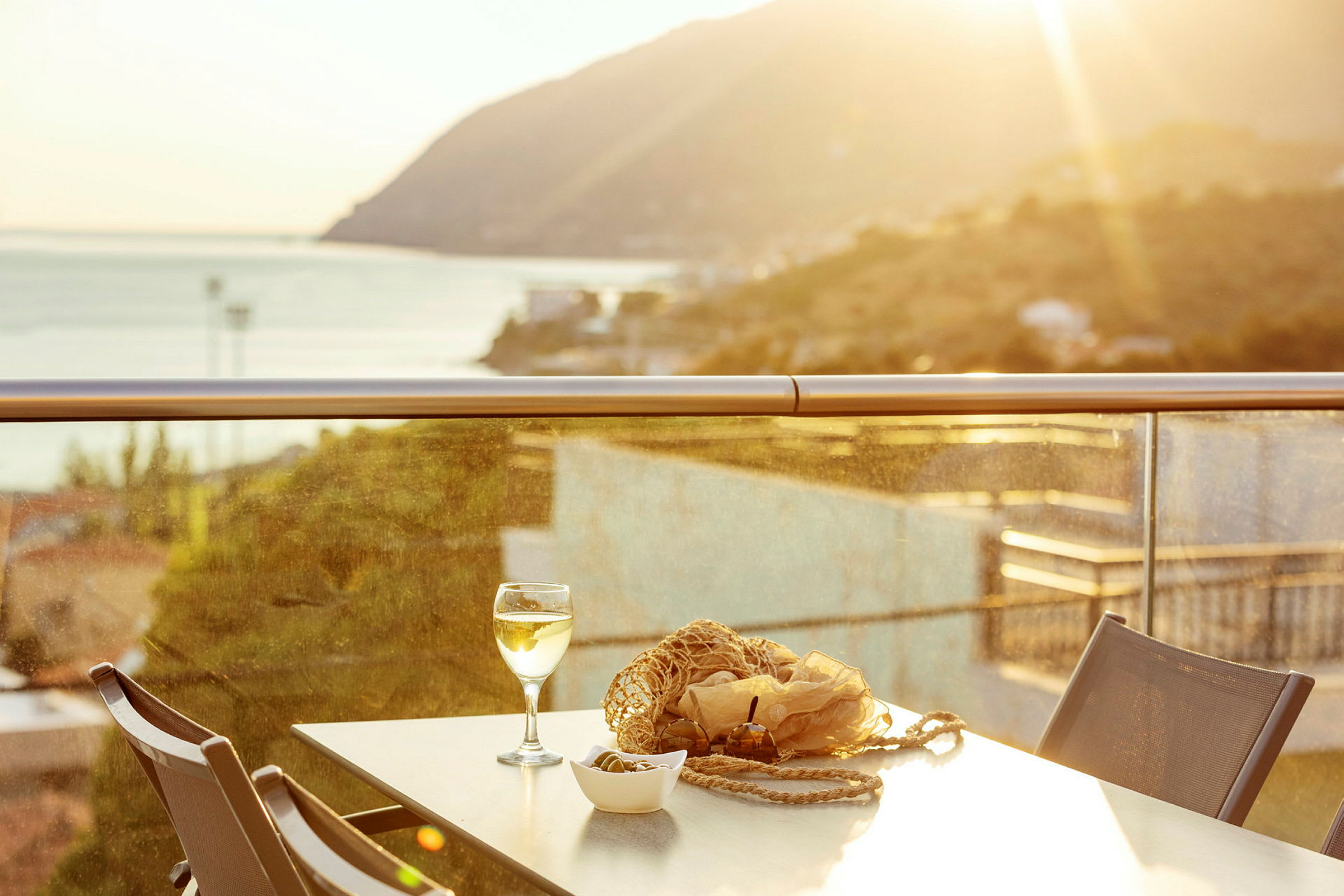 Bord med glas och snacks på en terrass med utsikt över ett solbelyst landskap. (AI-genererad text)