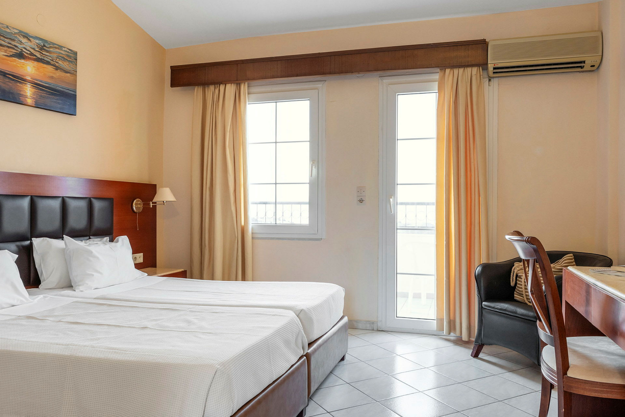 Hotellrum med två enkelsängar, skrivbord och fönster med ljusa gardiner. (AI-genererad text)