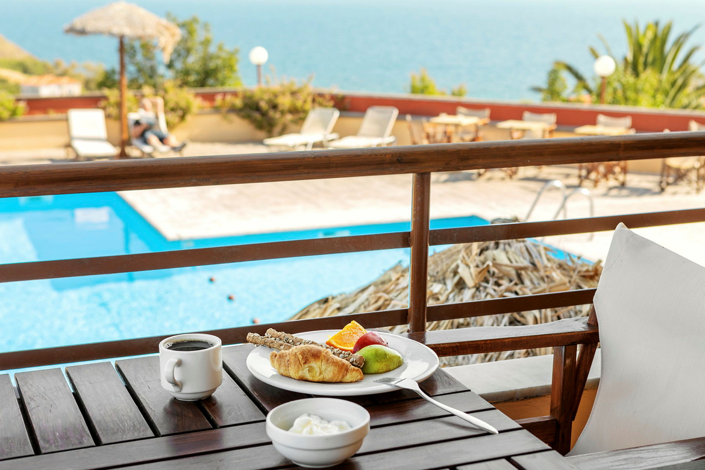 En tallrik med frukost vid ett bord med utsikt över en pool. (AI-genererad text)