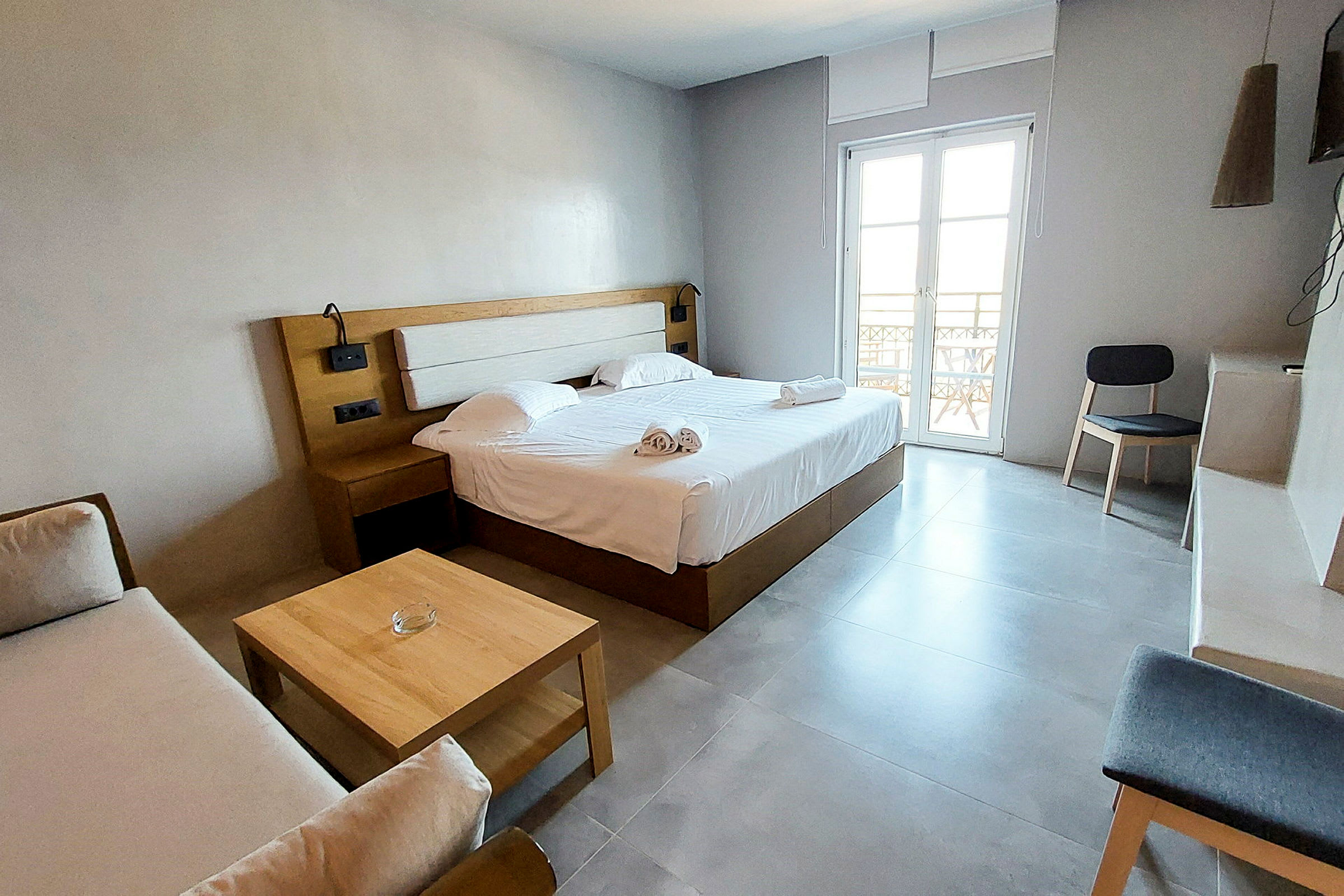 Modernt inrett hotellrum med dubbelsäng, soffa och trädetaljer. (AI-genererad text)