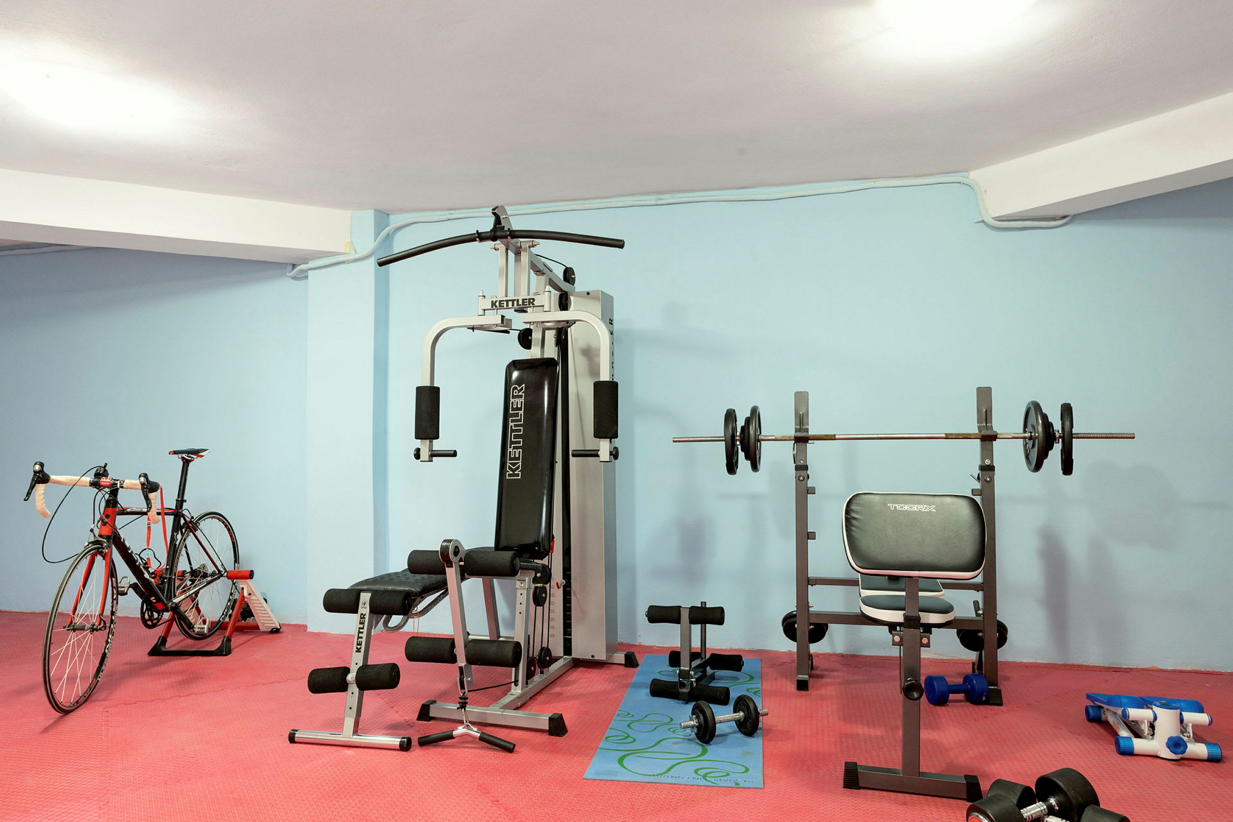 Ett gym med träningsutrustning inklusive en motionscykel, styrketräningsmaskiner och diverse vikter. (AI-genererad text)
