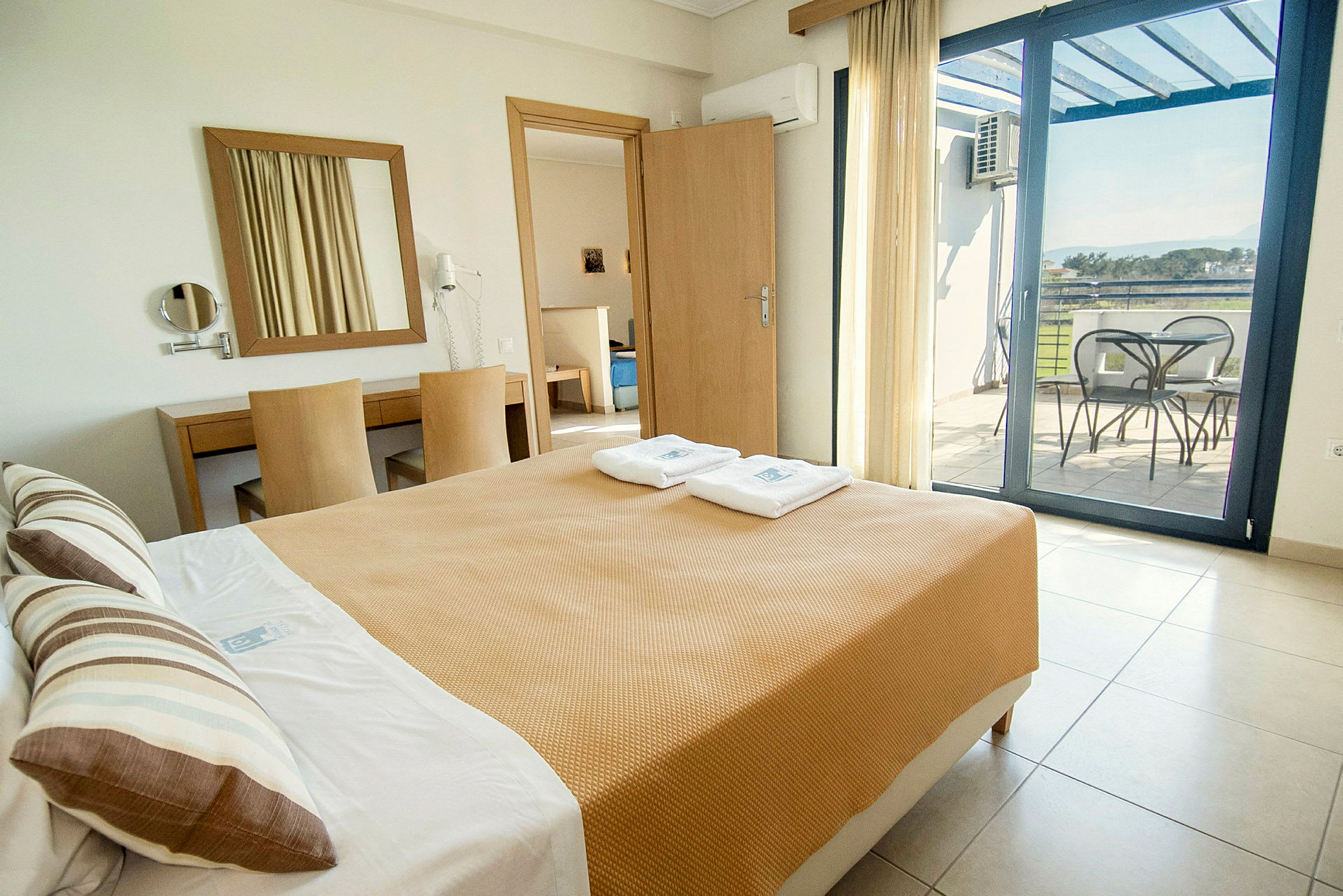 Bilden visar ett hotellrum med en säng, ett skrivbord och en balkong med utsikt. (AI-genererad text)