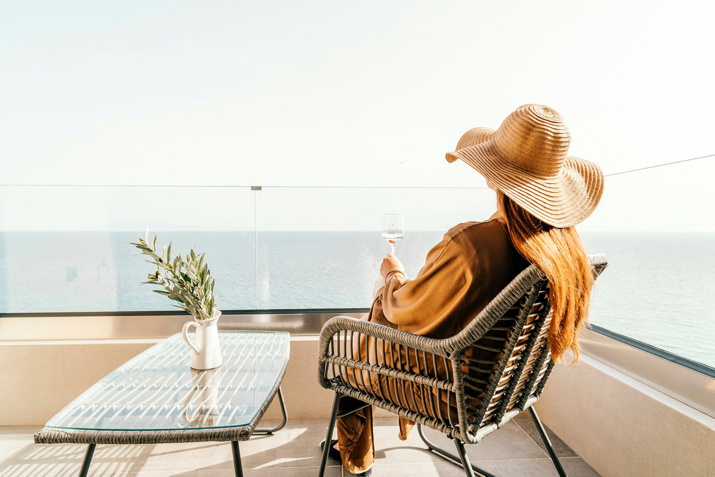 En person med solhatt som sitter på en terrass vid havet. (AI-genererad text)