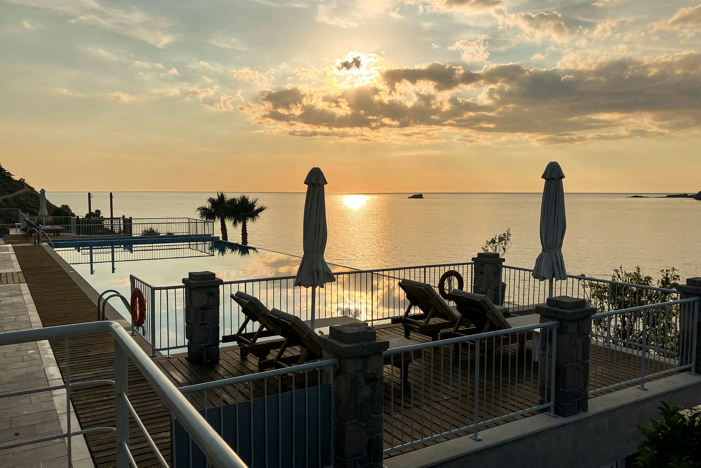 Solnedgång över en poolområde med utsikt mot havet. (AI-genererad text)