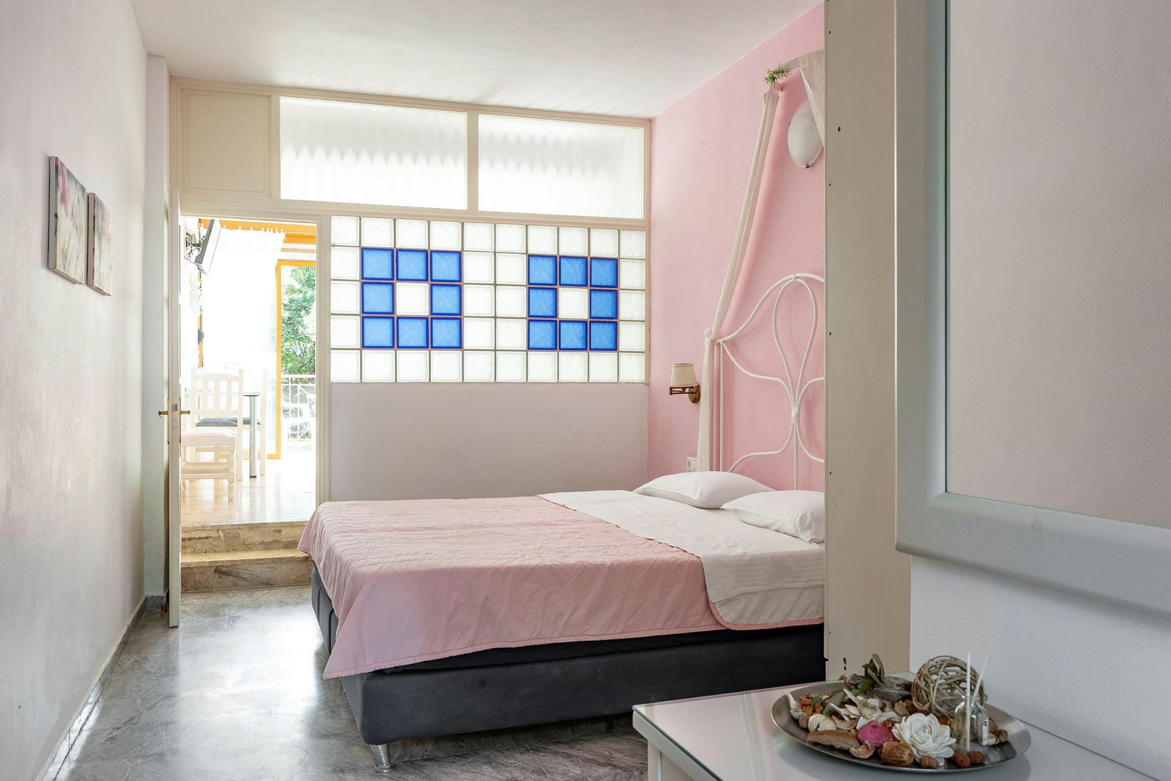 Hotellrum med dubbelsäng som har rosa överkast och en rosa vägg. (AI-genererad text)
