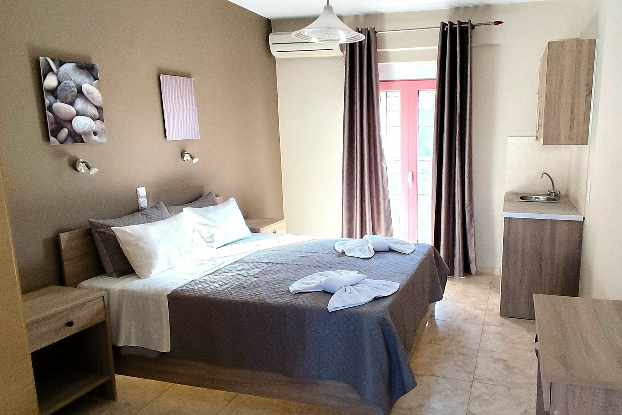 Ett hotellrum med dubbelsäng, väggdekorationer och ett litet kök. (AI-genererad text)