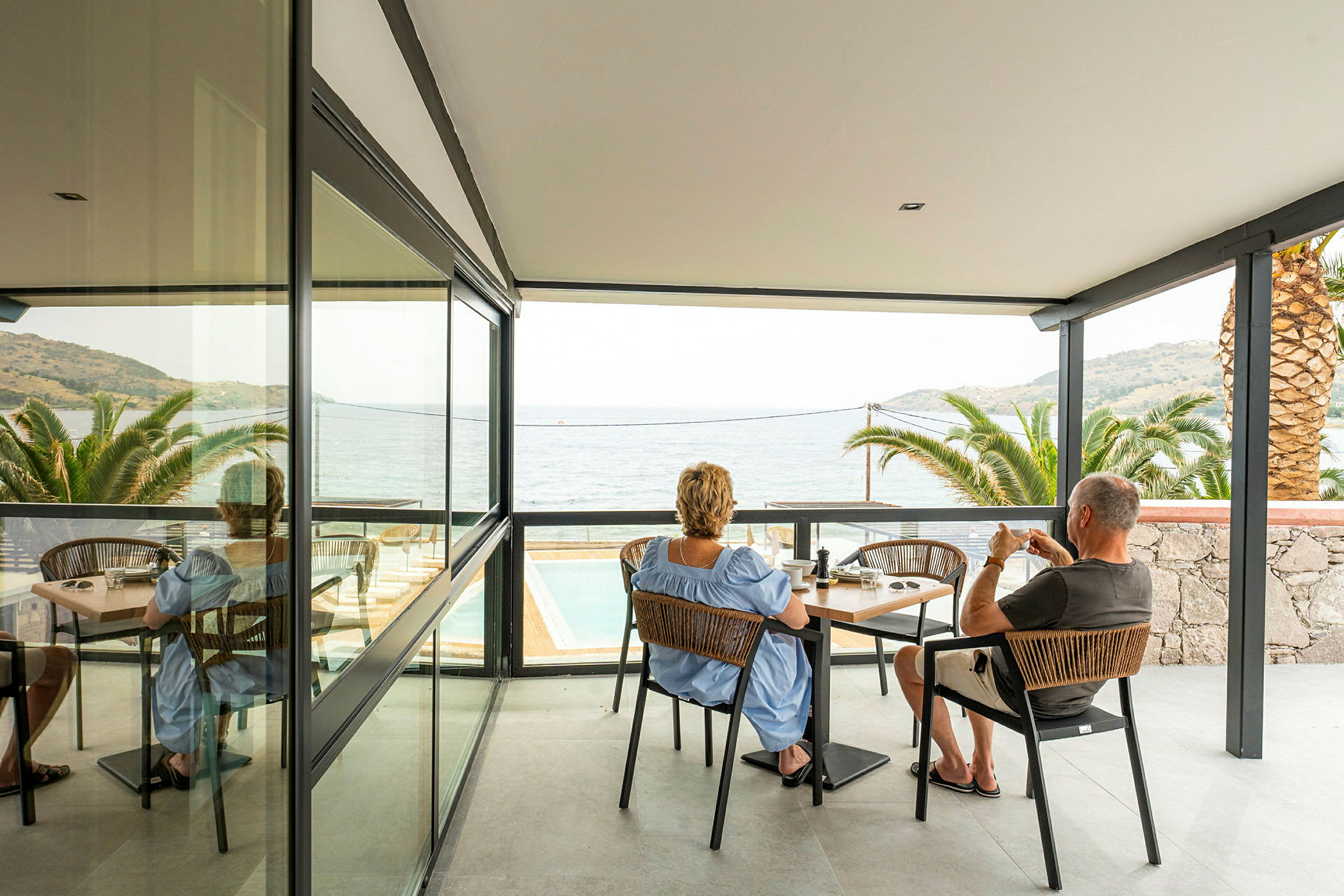 Två personer sitter vid ett bord på en uteplats med utsikt mot havet. (AI-genererad text)
