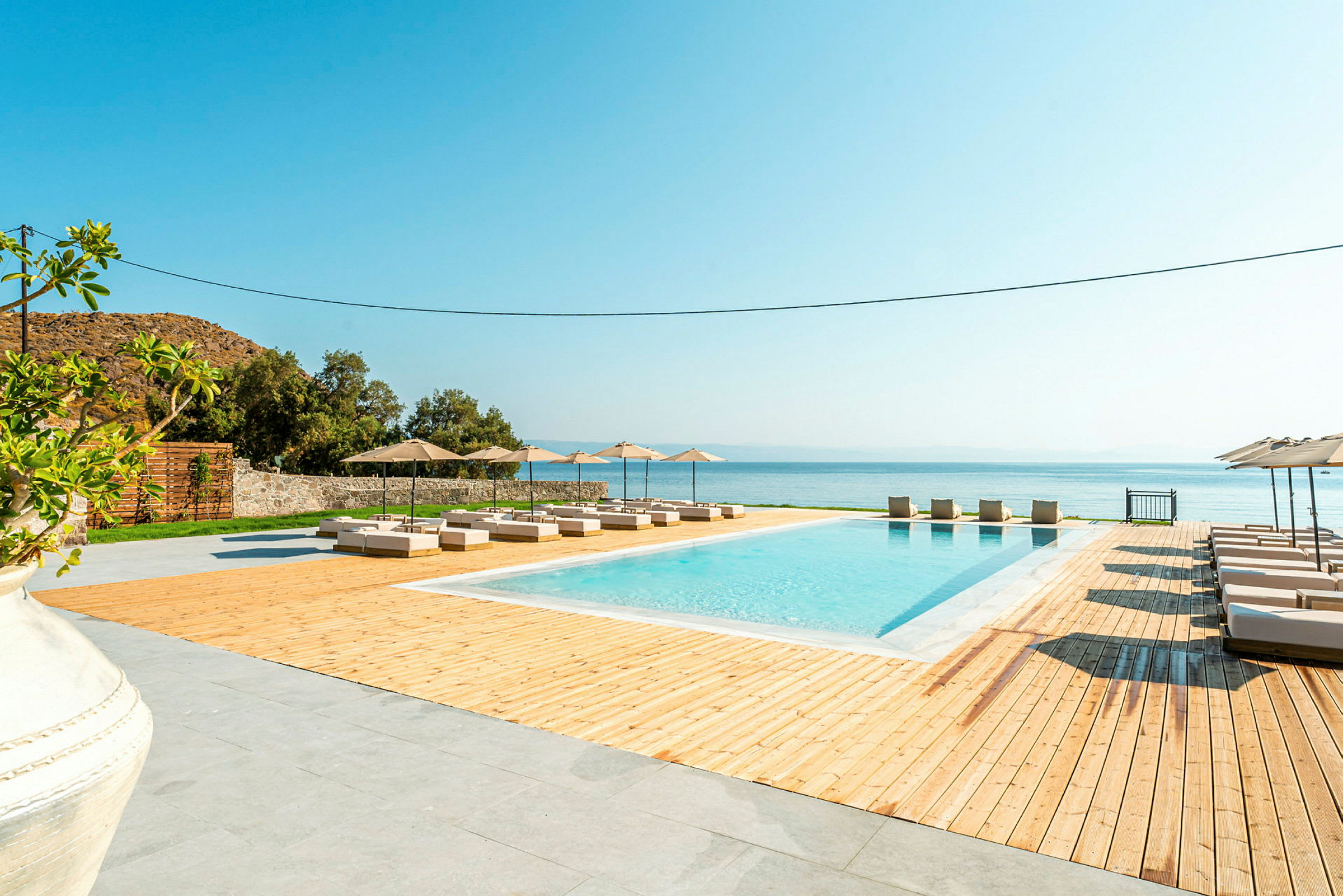 Poolområde med solstolar och parasoll vid havet. (AI-genererad text)