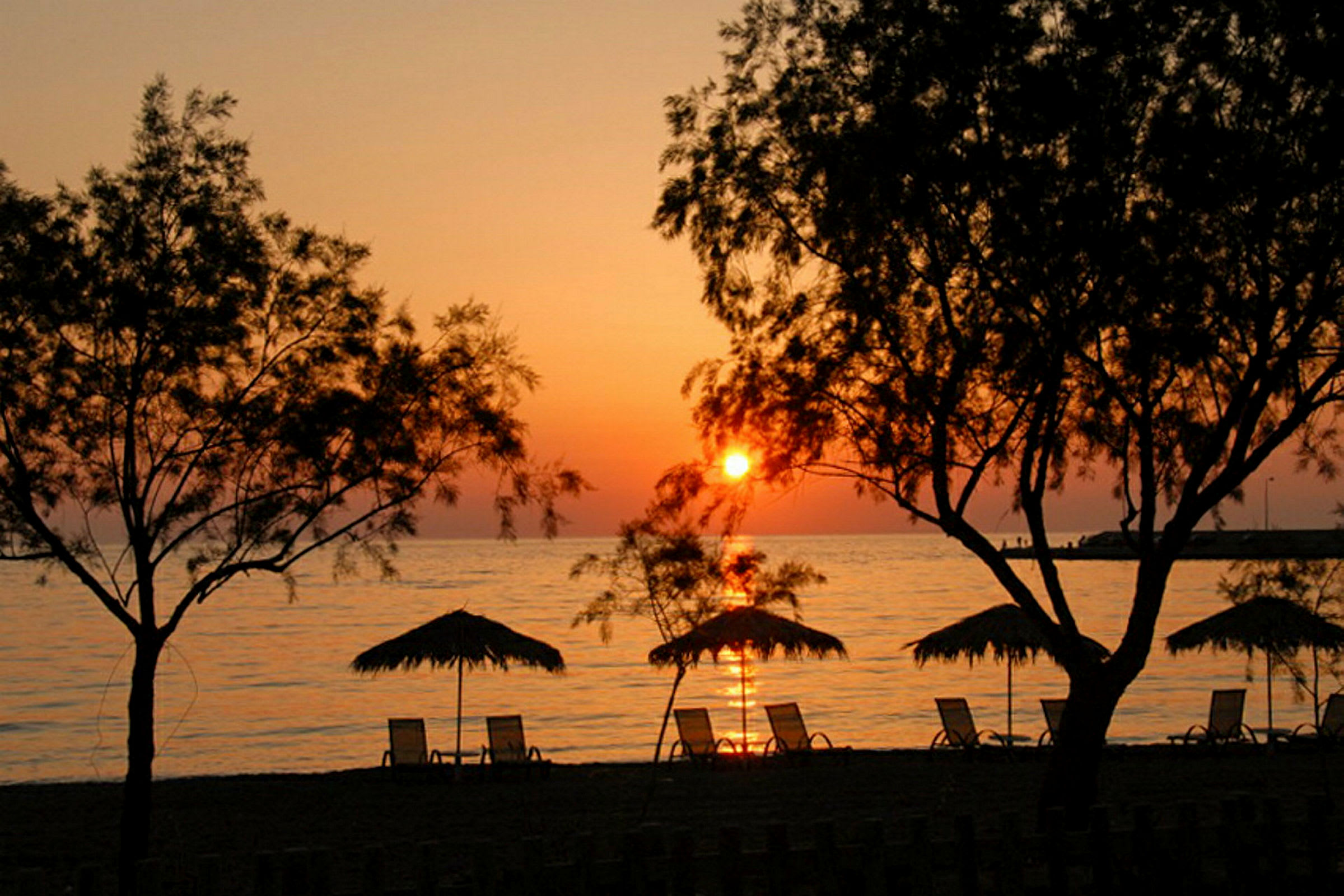 Strand med parasoller och solstolar vid solnedgång. (AI-genererad text)