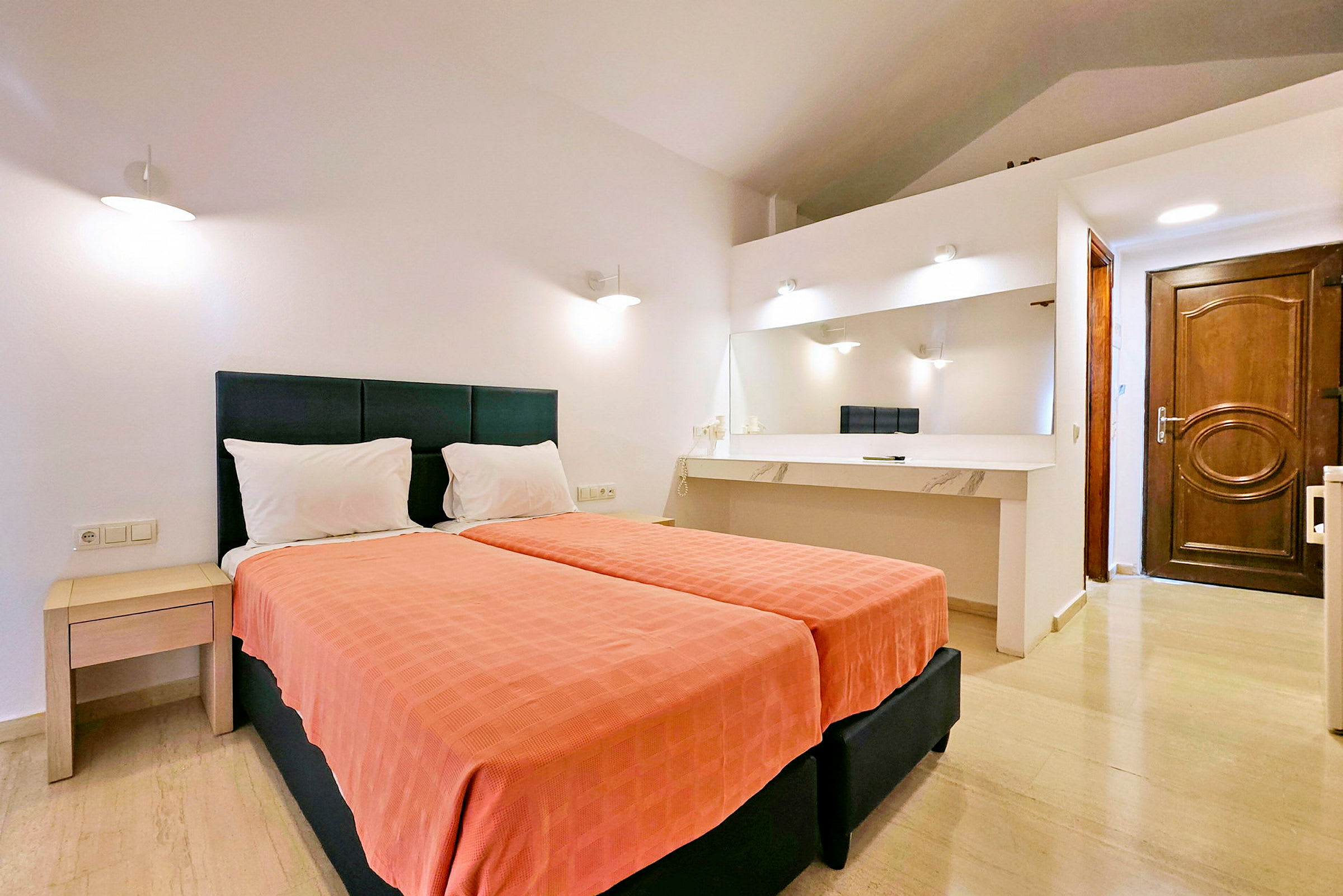 Hotellrum med två enkelsängar, ett skrivbord med spegel och vita väggar. (AI-genererad text)