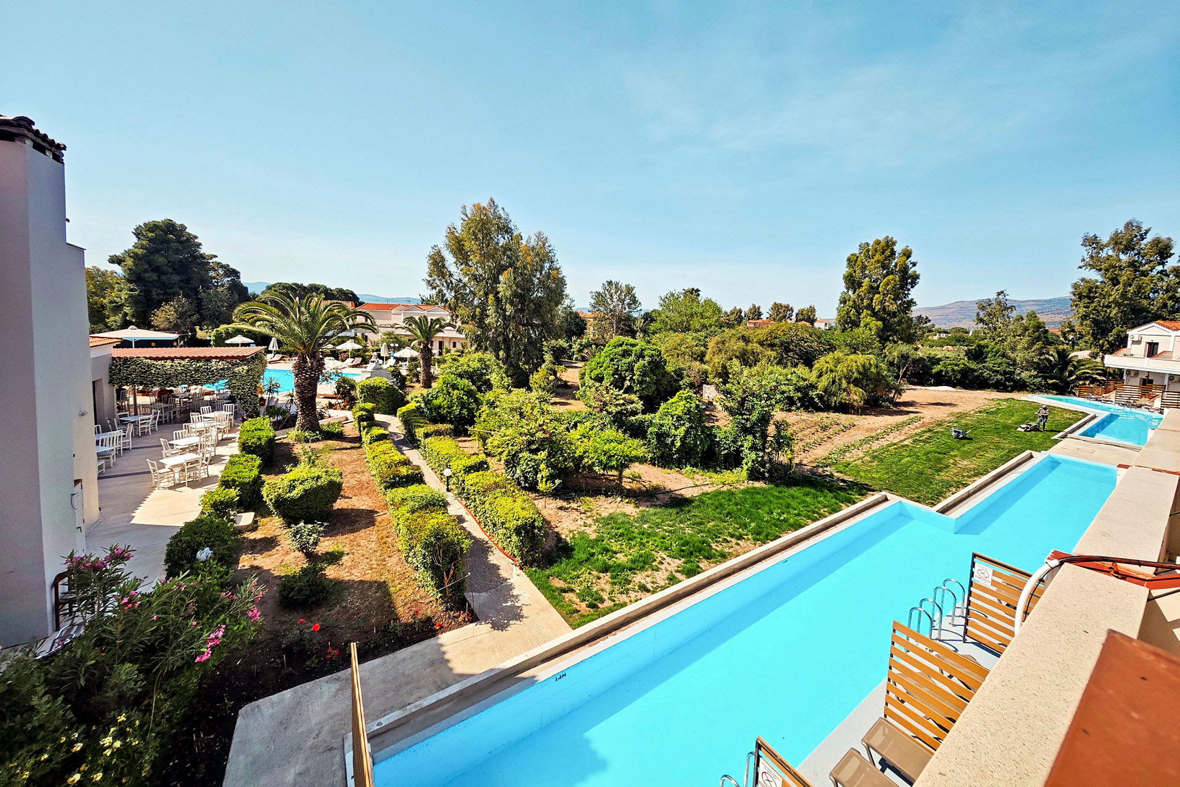 Hotellområde med trädgård, pool och grönska. (AI-genererad text)
