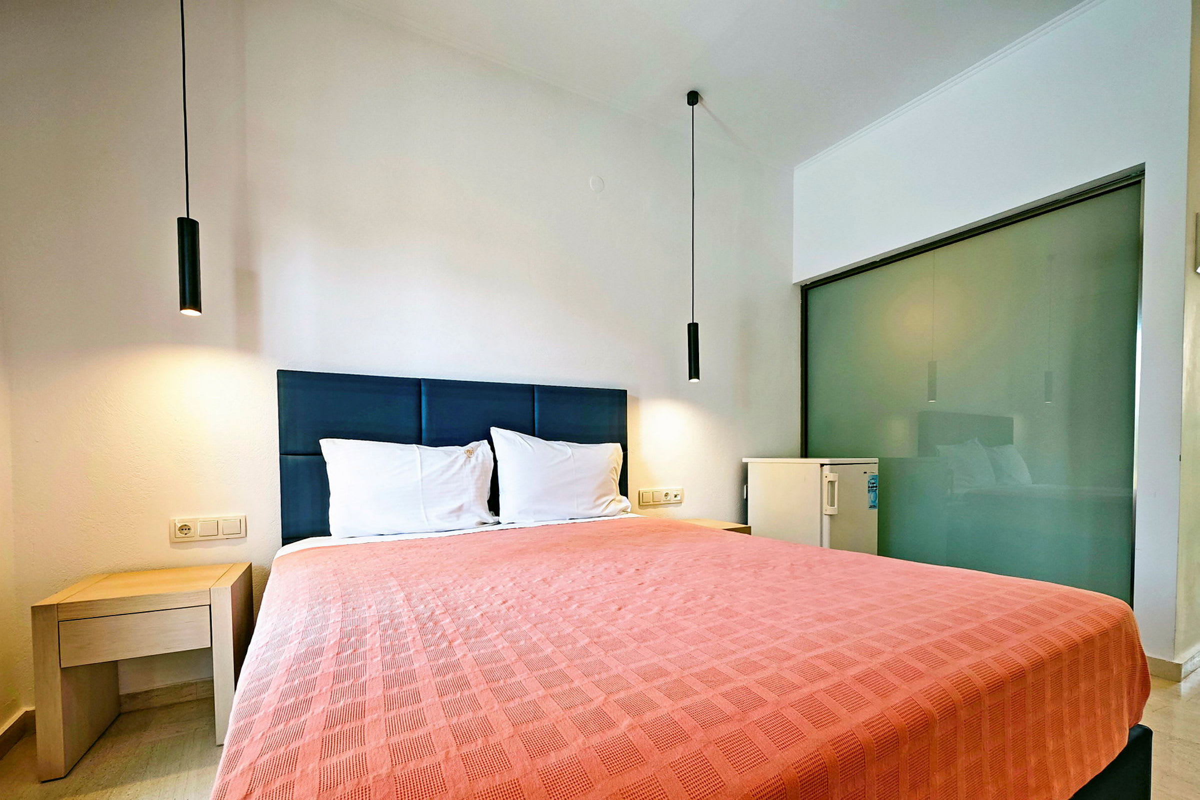 Hotellrum med en dubbelsäng och enkel inredning. (AI-genererad text)