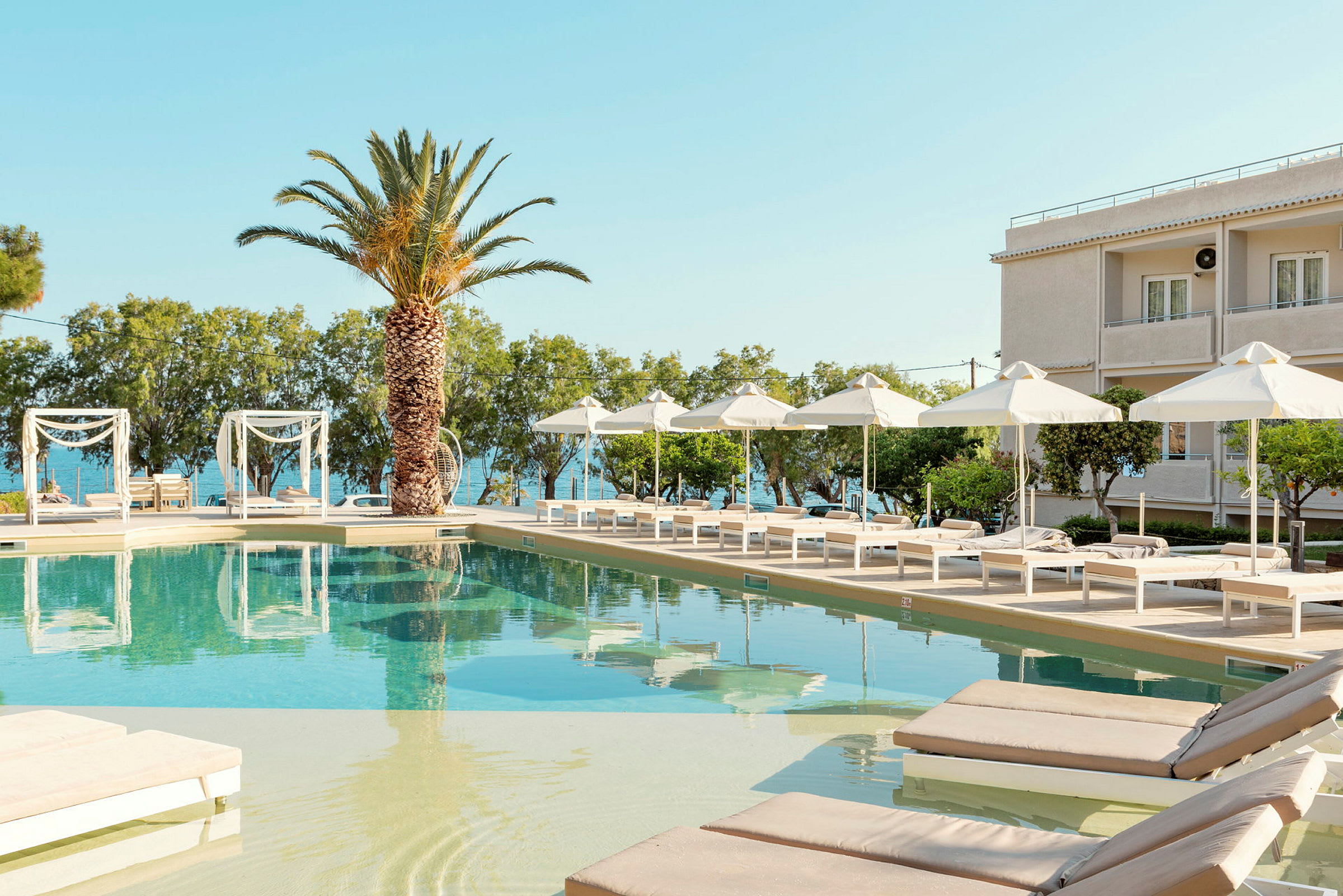 En pool med solstolar och parasoller vid ett hotell med havsutsikt. (AI-genererad text)