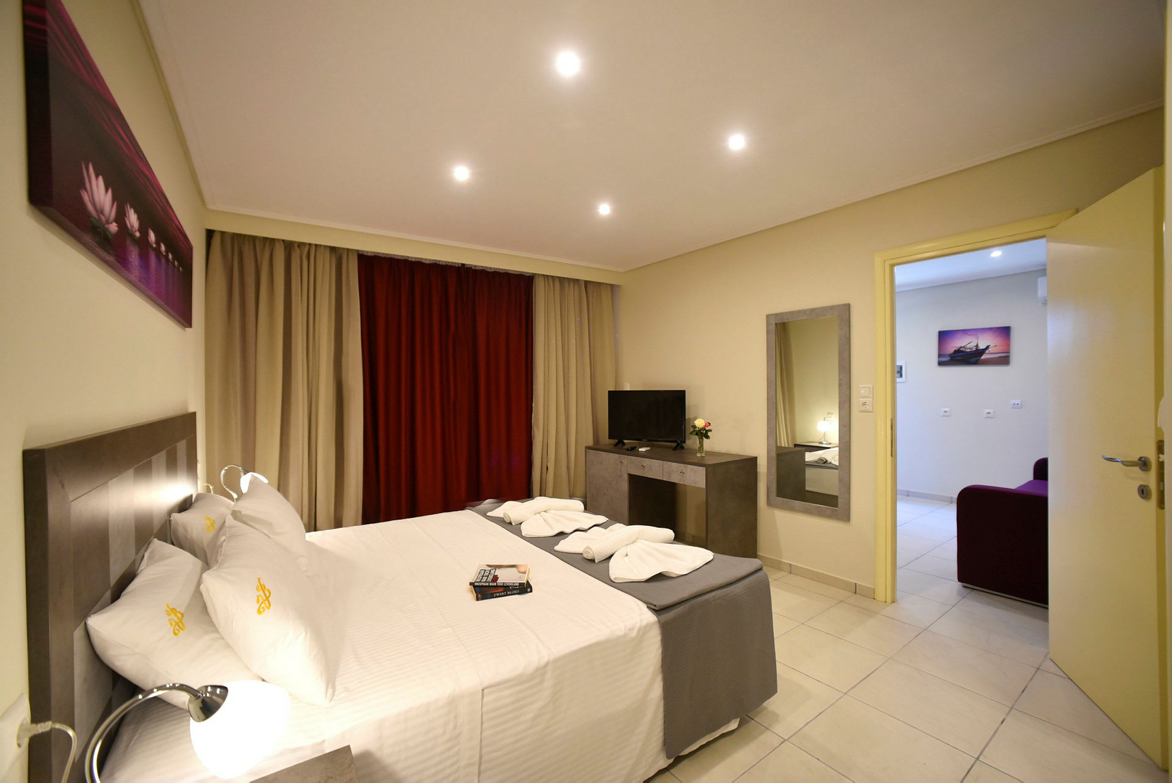 Hotellrum med dubbelsäng, TV och fönster med gardiner. (AI-genererad text)