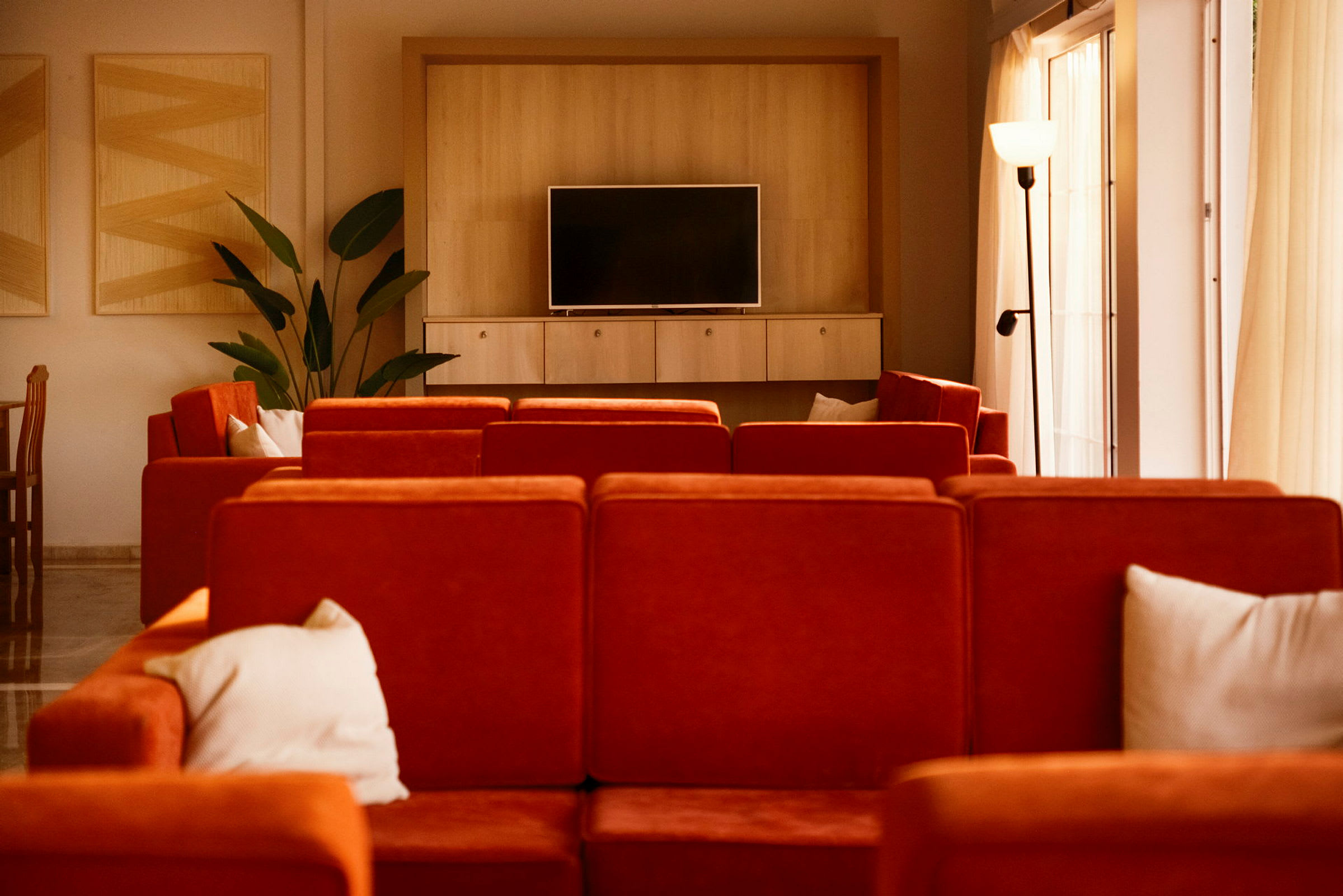Ett vardagsrum med röda soffor, en TV på en träbänk och dekorationer. (AI-genererad text)