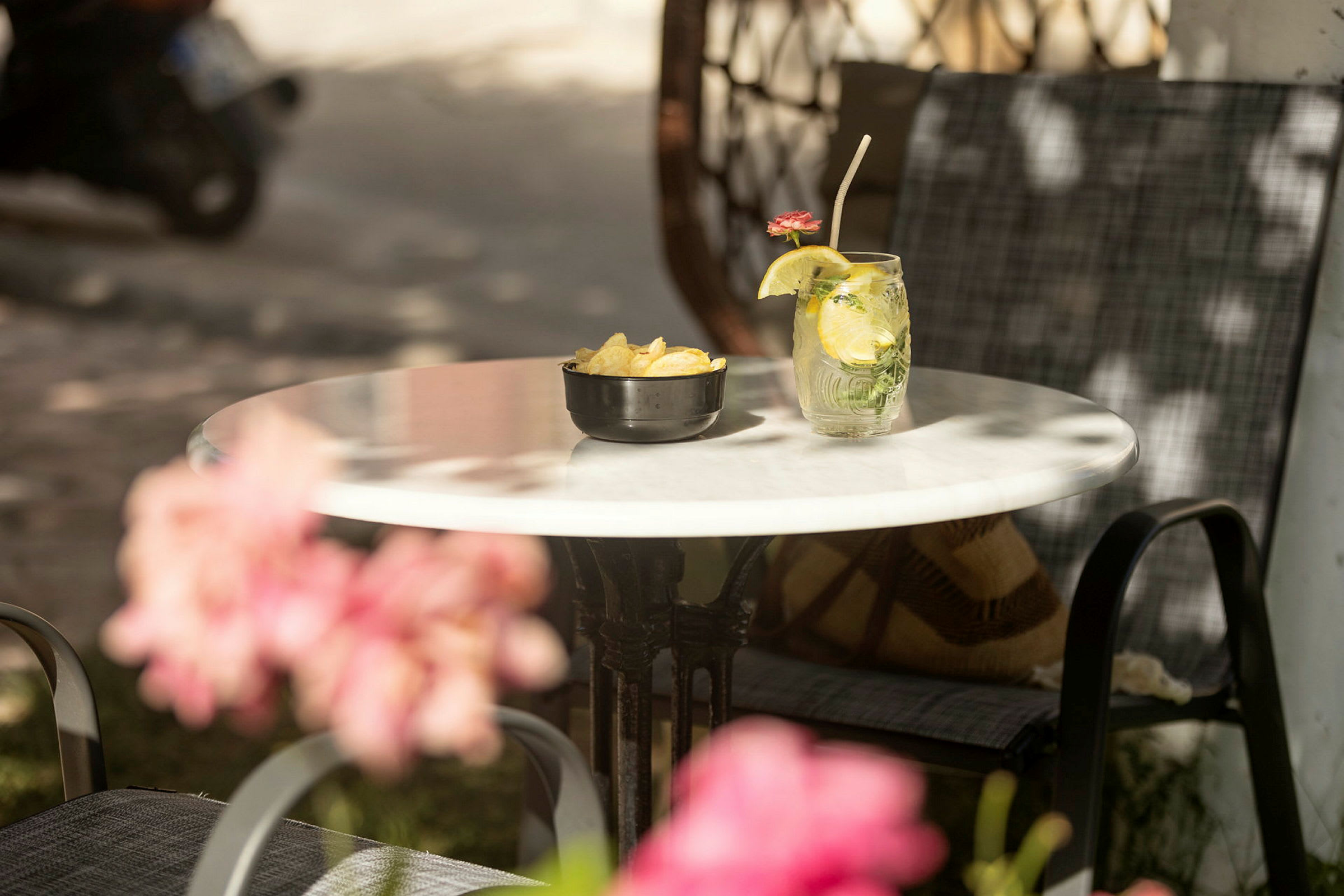 Ett bord med en skål chips och ett glas med en drink dekorerat med en citronskiva och en blomma. (AI-genererad text)