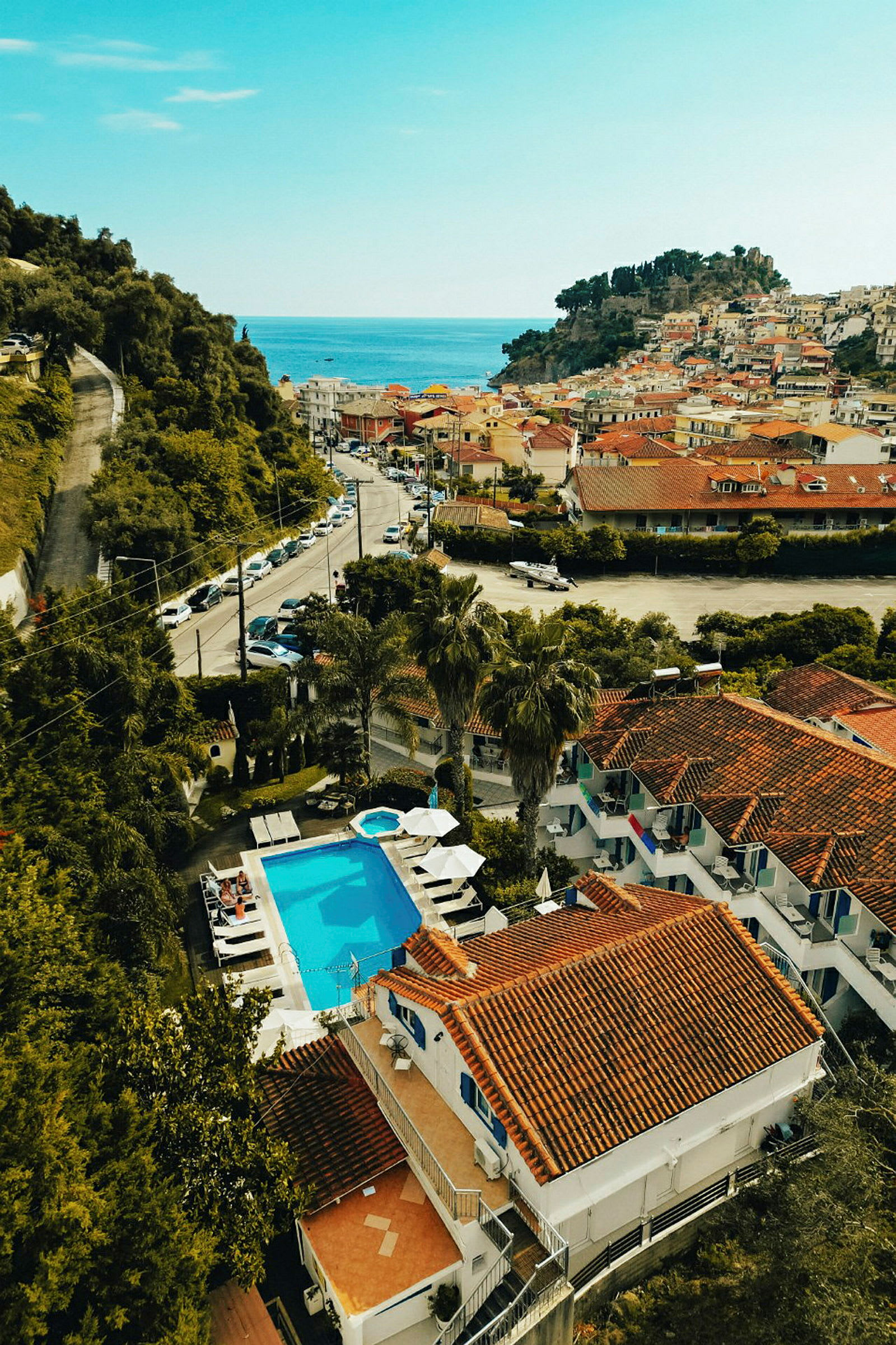 Vy över en liten stad med röda tak, pool och havet i bakgrunden. (AI-genererad text)