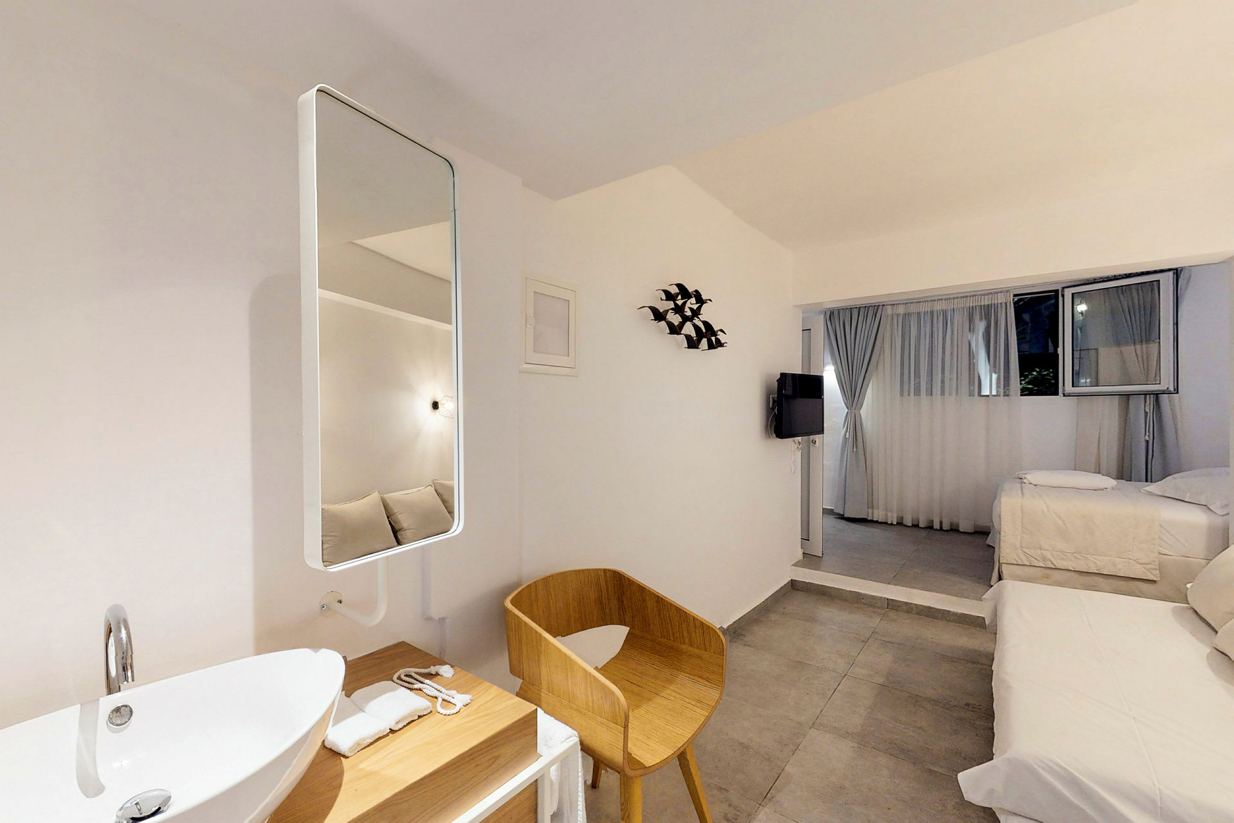 Modernt och ljust hotellrum med sängar, en sittplats och ett handfat. (AI-genererad text)