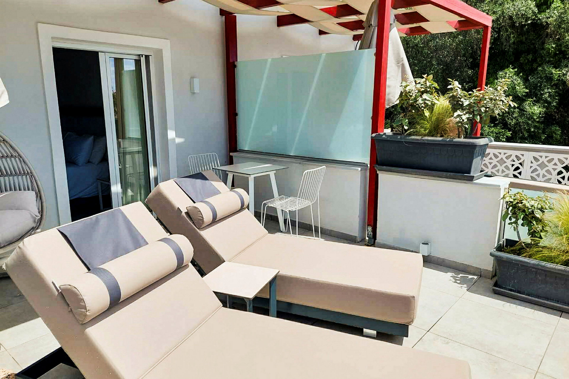 Terrass med två solstolar och ett bord med två stolar under en pergola. (AI-genererad text)