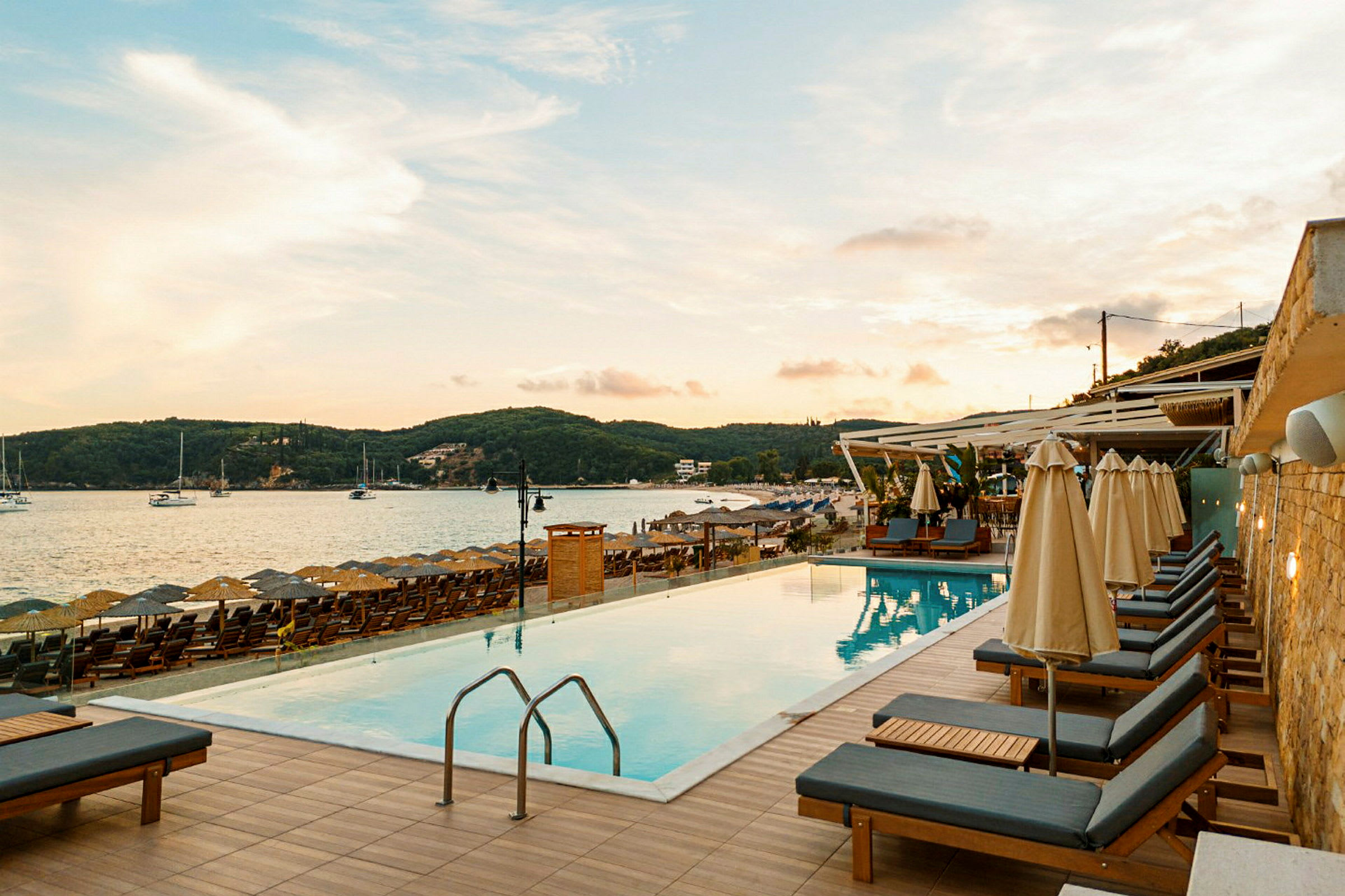Pool med solstolar vid strand med havsutsikt. (AI-genererad text)