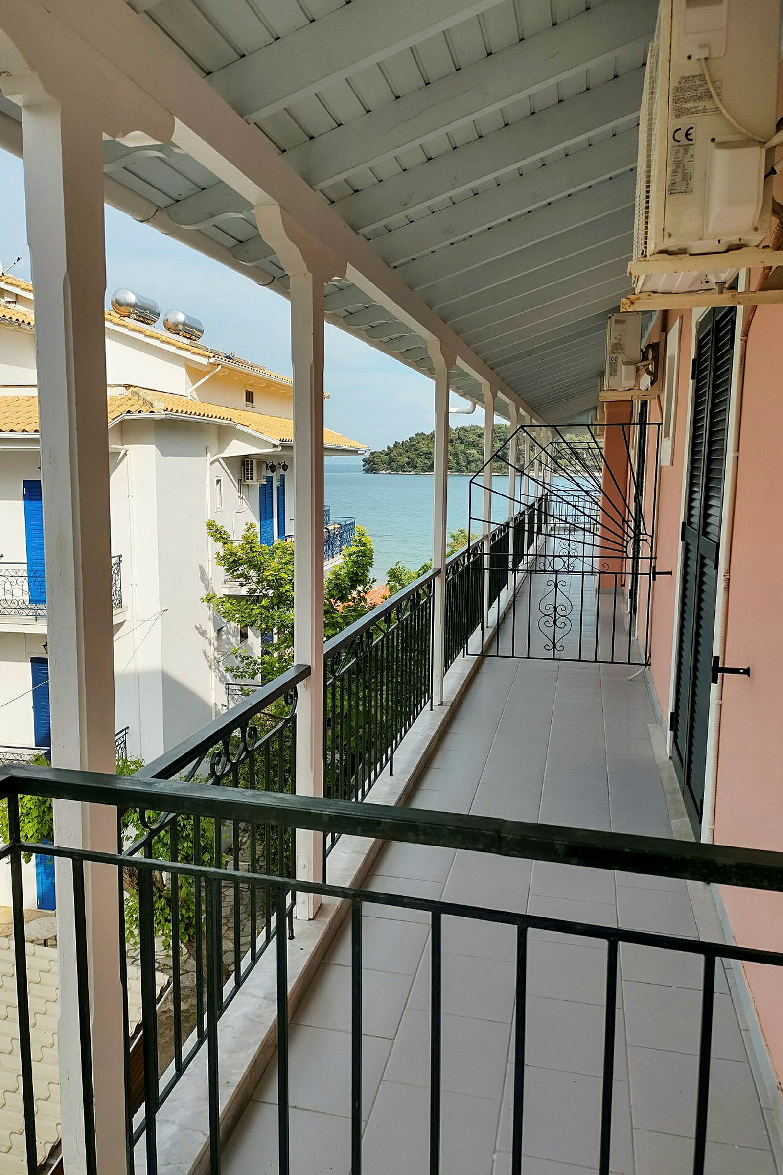 En balkong med räcke, utsikt mot en byggnad och havet. (AI-genererad text)