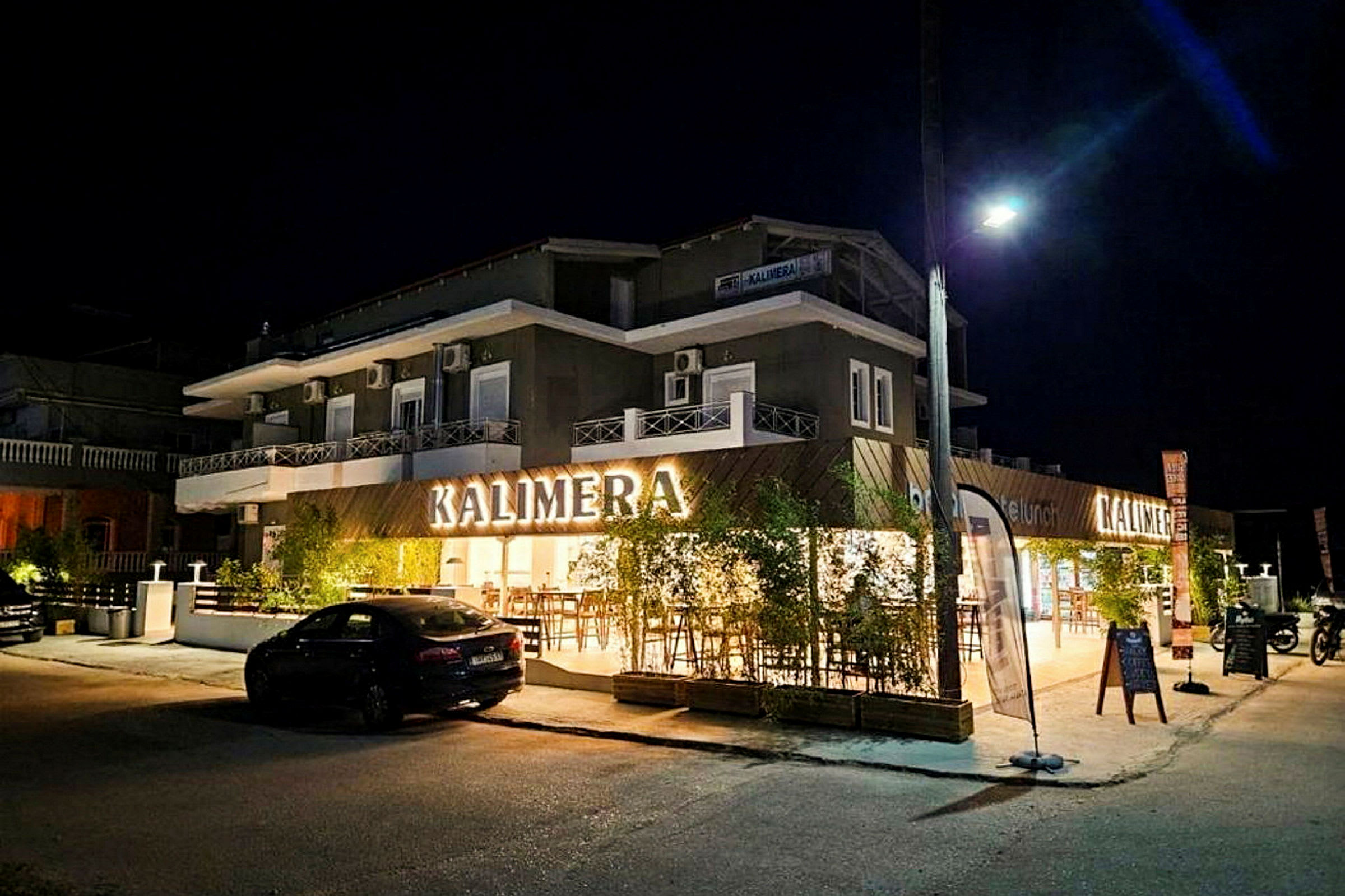 En fasad av en byggnad med skylten 'KALIMERA', tagen på kvällen. (AI-genererad text)