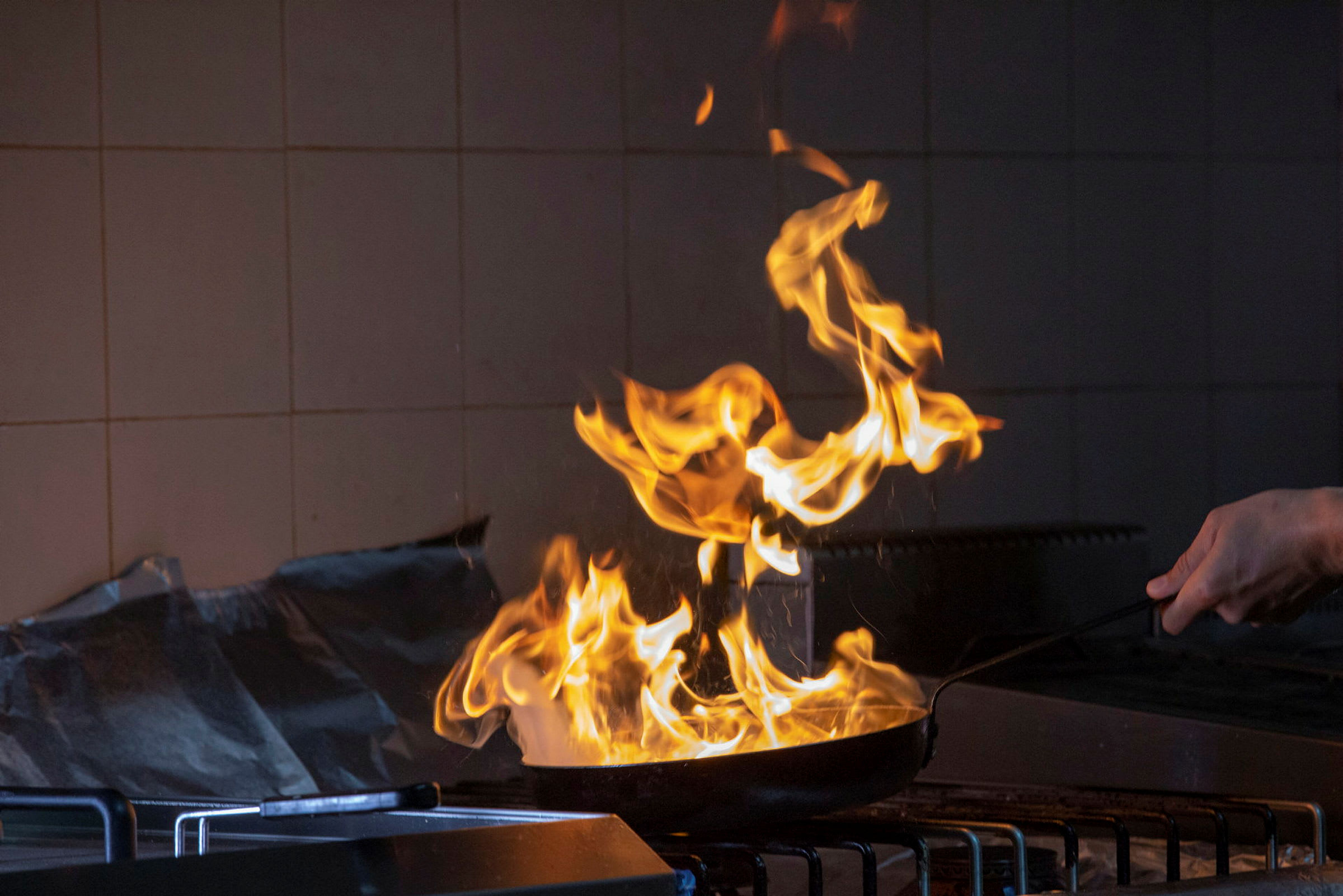 Eldflammor från en stekpanna på en spis. (AI-genererad text)