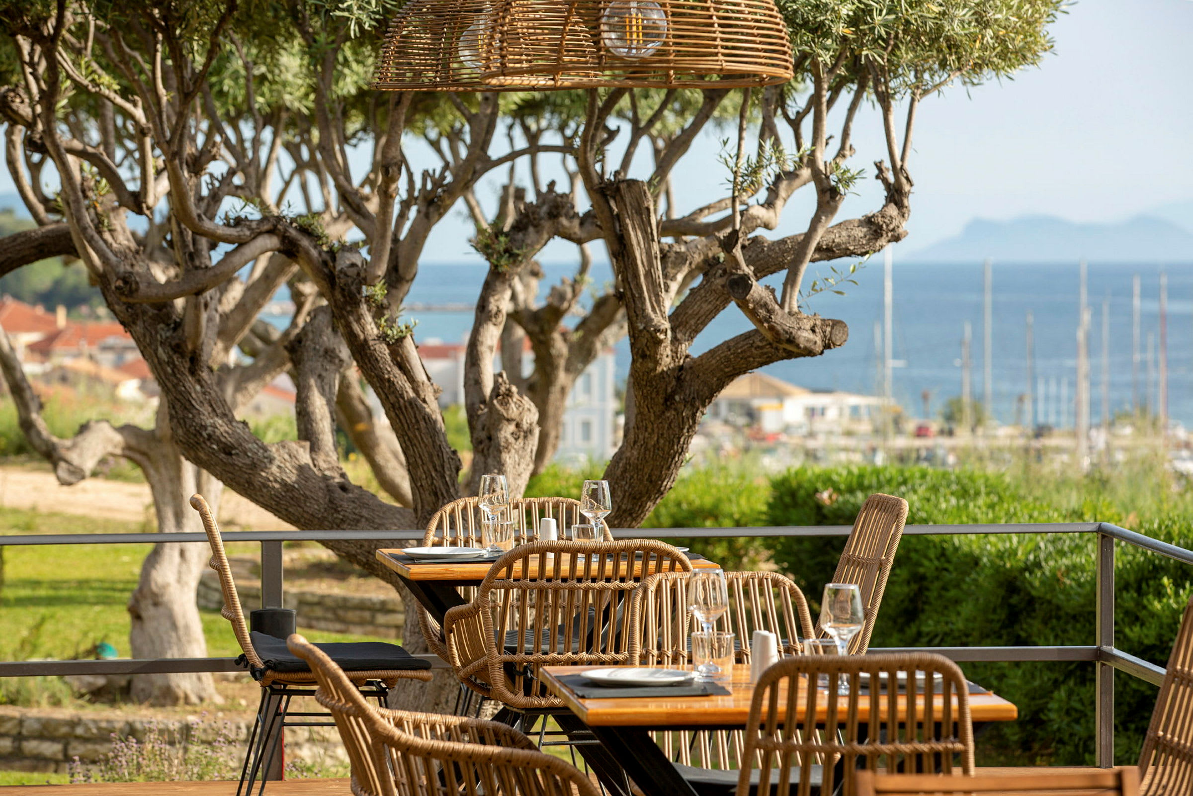 Uteservering med rottingstolar och utsikt över havet. (AI-genererad text)