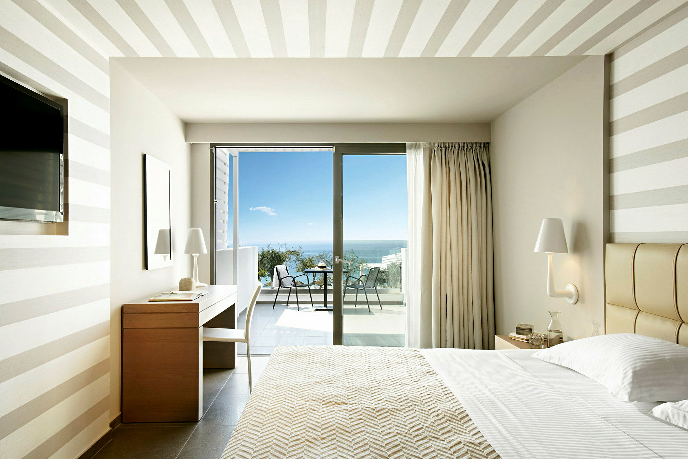 Modern hotellrum med utsikt mot havet genom glasdörrar. (AI-genererad text)